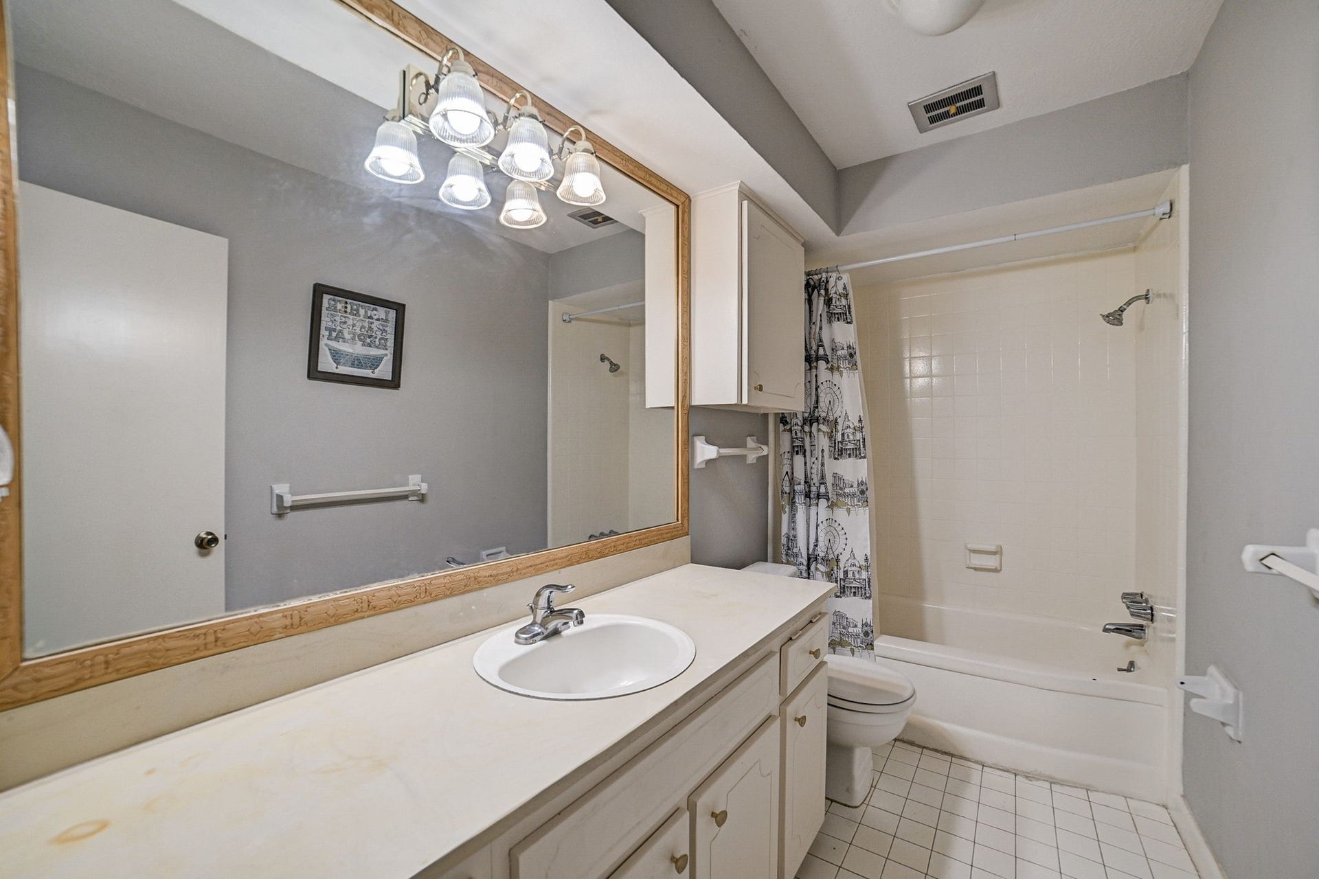 7900 Westheimer Road, #202, Houston, TX 77063 Bright bathroom featuring a large mirror, ample counter space, and a shower-tub combo with a decorative curtain.