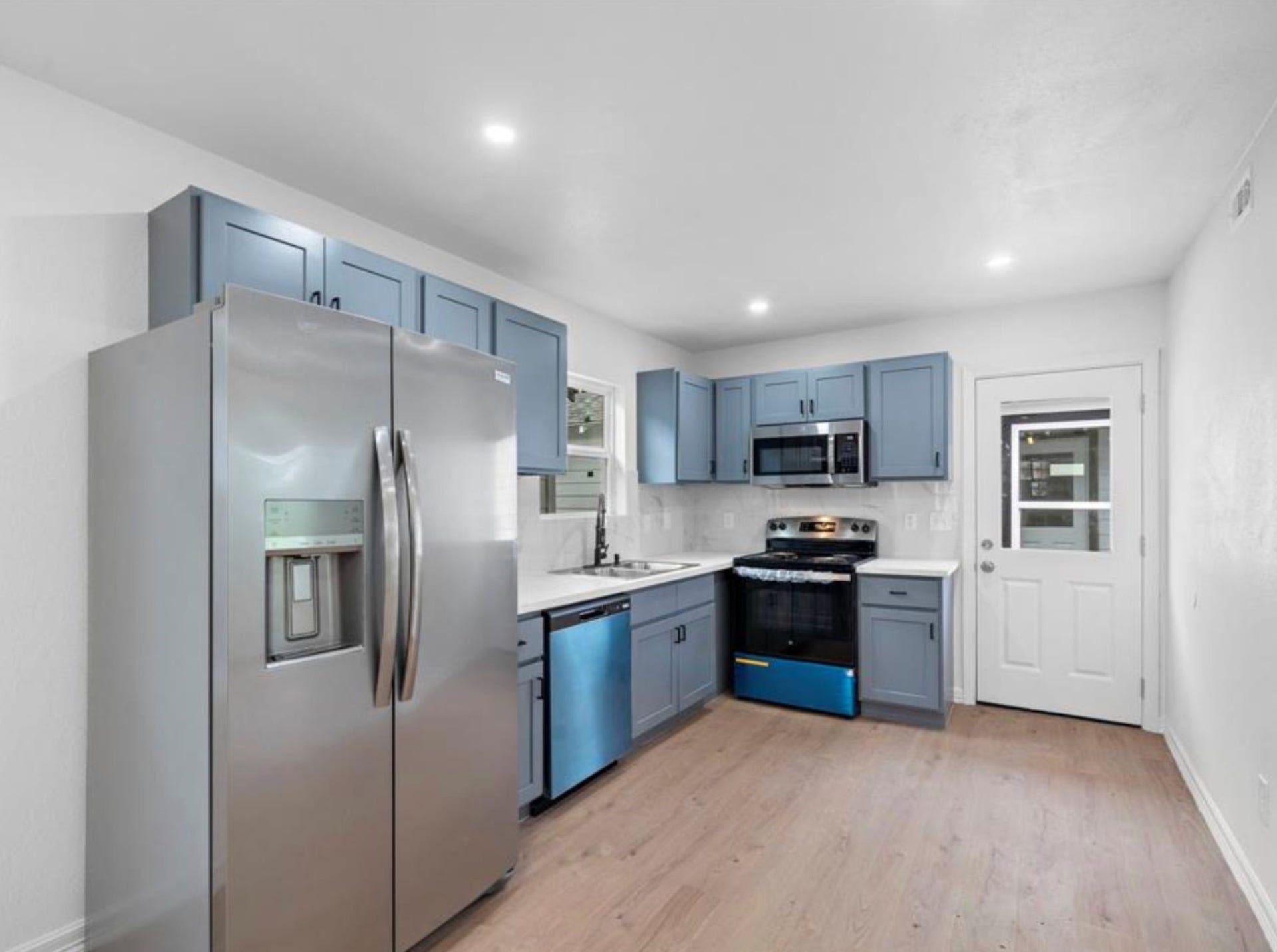 2314 Lucinda Street, Houston, TX 77004 Kitchen with blue cabinetry and stainless steel appliances.