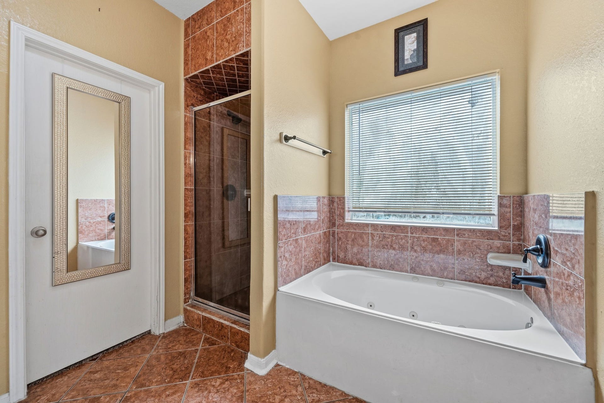 Elegant bathroom featuring a luxurious soaking tub and separate glass-enclosed shower, complemented by warm tile accents and ample natural light.