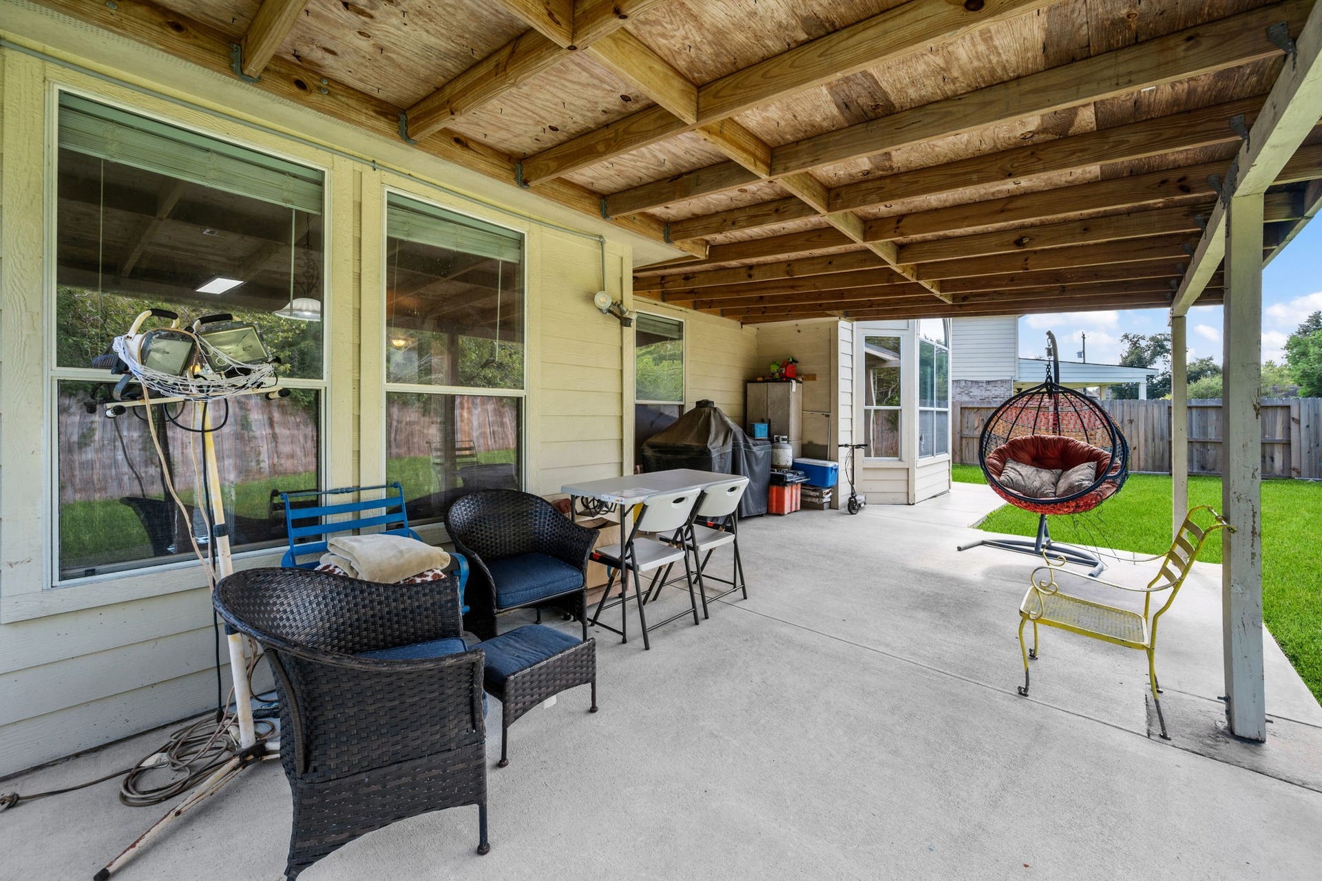 Spacious covered patio with cozy seating, perfect for outdoor relaxation and entertaining, overlooking a lush green yard.