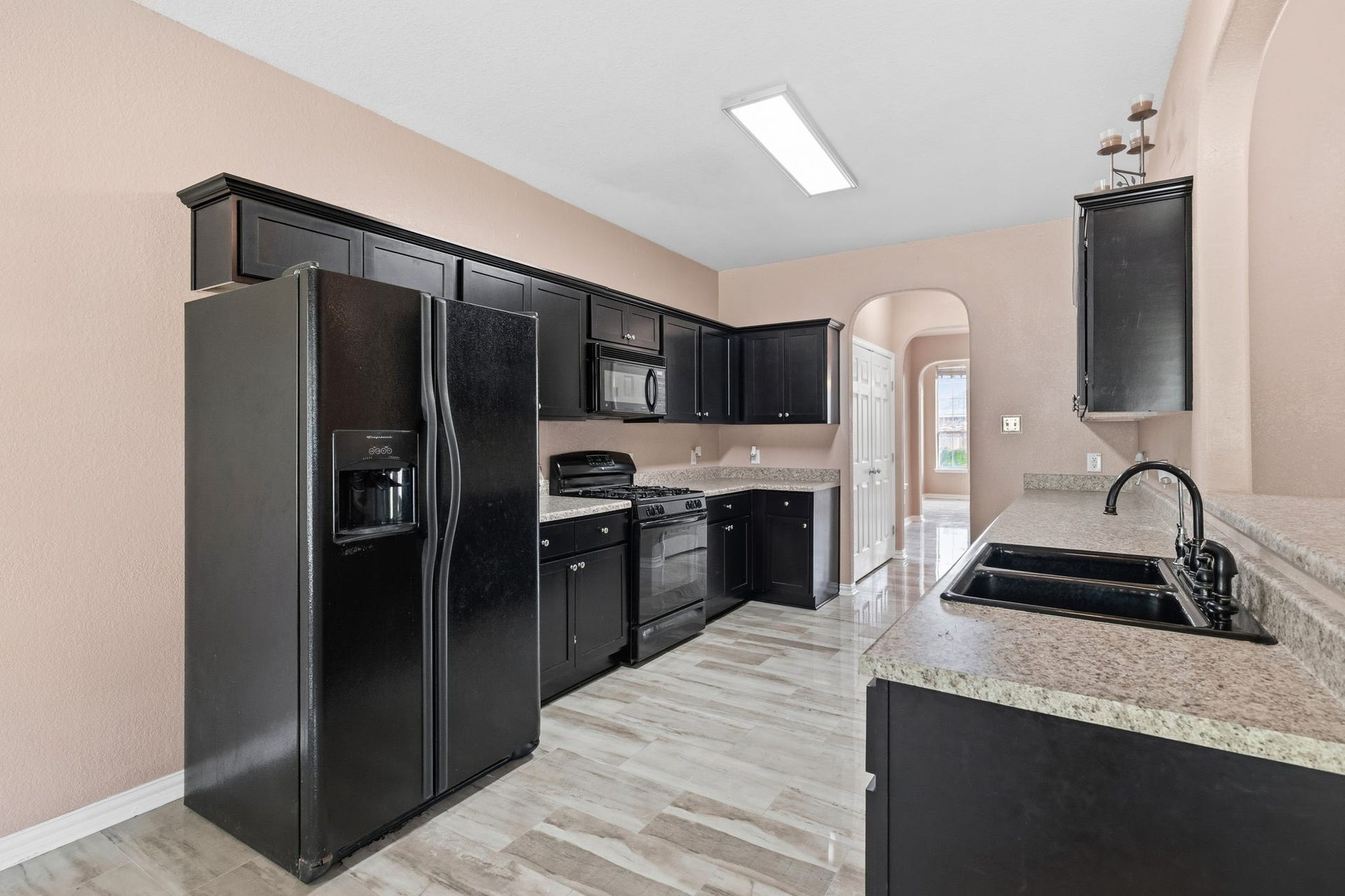 Sleek kitchen featuring modern black appliances, ample cabinetry, and elegant granite countertops, perfect for culinary enthusiasts.