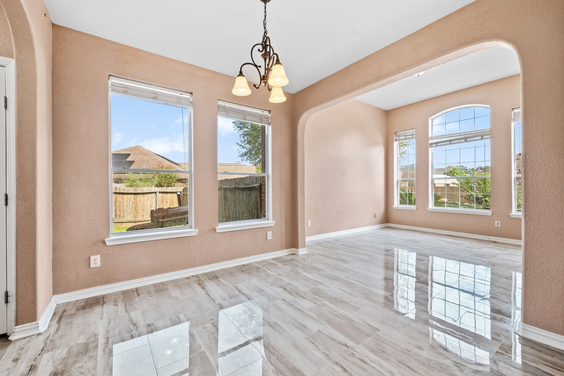 Bright and inviting space with large windows, elegant tile flooring, and an open layout perfect for dining and entertaining.