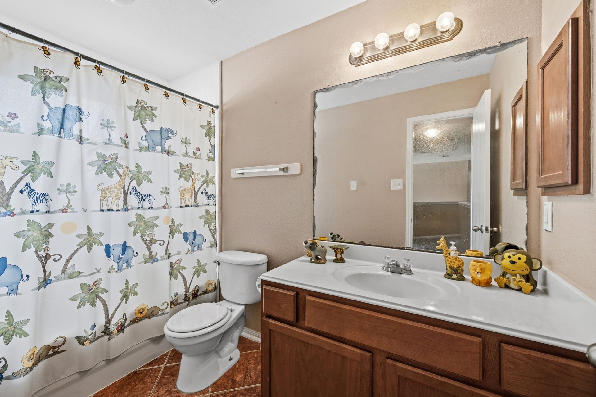 Charming bathroom with playful safari-themed shower curtain, spacious vanity, and warm wood cabinetry, perfect for adding a touch of fun to your daily routine.