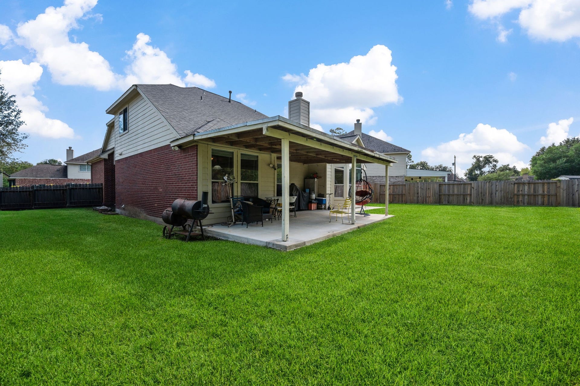 Charming home with a spacious backyard featuring a covered patio, perfect for outdoor entertaining and relaxation.