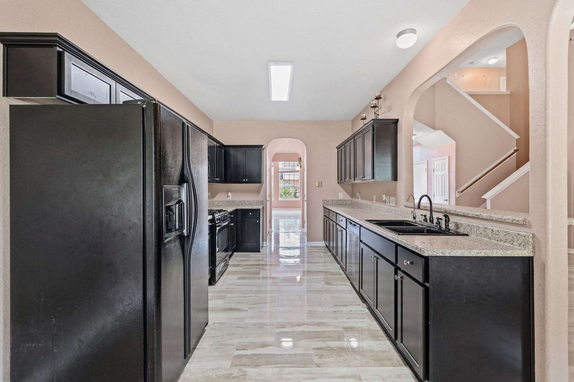 Sleek kitchen featuring granite countertops, dark cabinetry, and modern appliances, complemented by a spacious layout and elegant tile flooring.