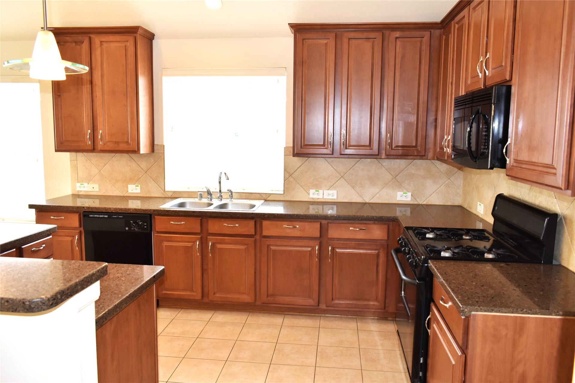 4822 Harbor Glen Lane, Houston, TX 77084 Spacious kitchen featuring rich wood cabinetry, sleek dark countertops, and modern appliances, perfect for culinary enthusiasts.