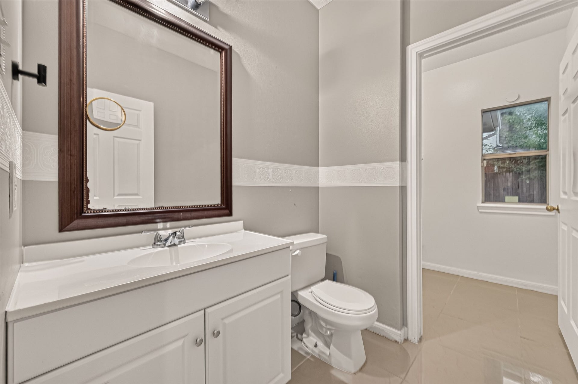 22818 Williamschase Drive, Katy, TX 77449 Half bath on the first floor featuring a spacious white vanity, framed mirror in neutral tones