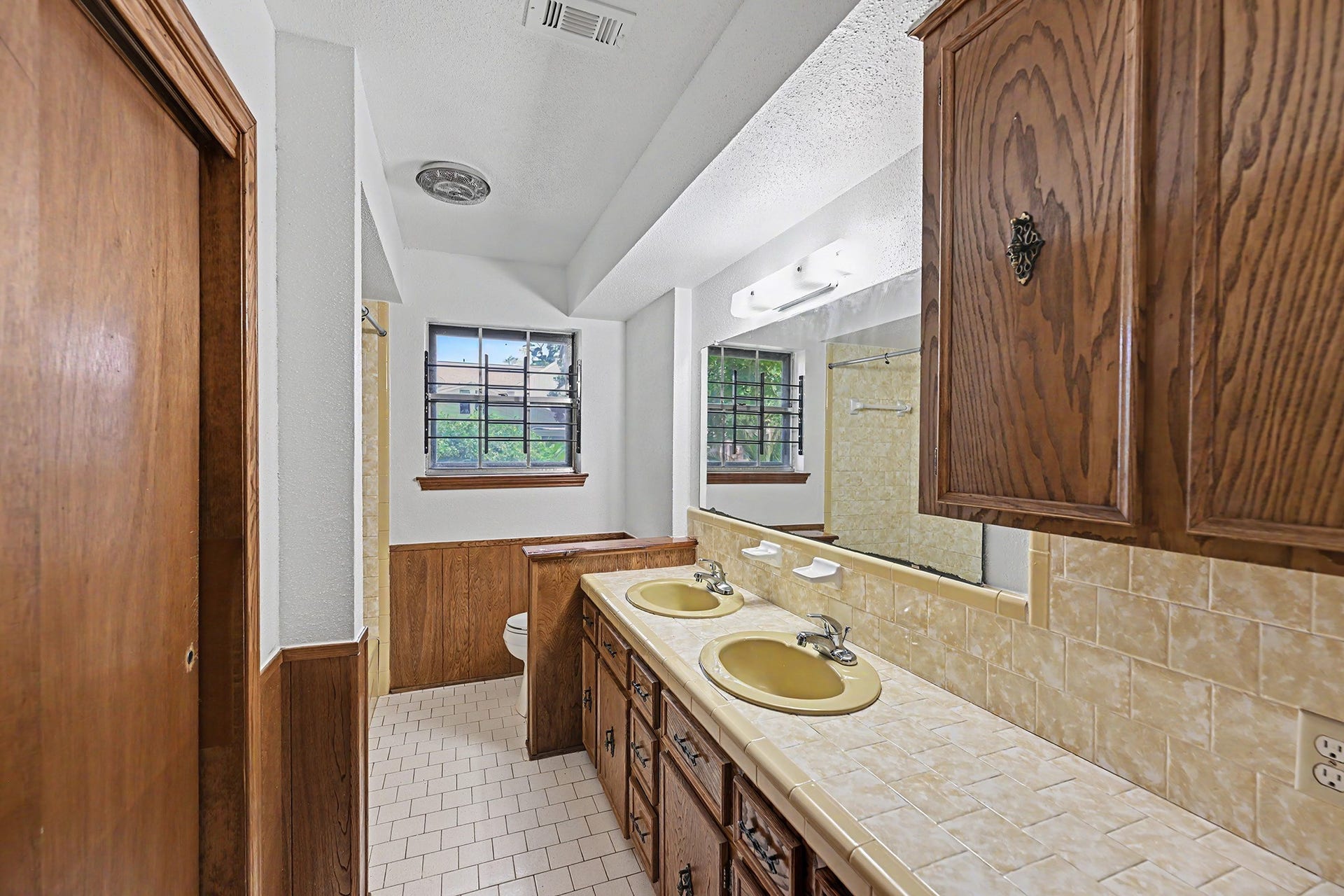 5403 Boots Road, Houston, TX 77091 Secondary bathroom with solid wood cabinets, shower tub combo & tiled countertop & backsplash with dual sinks