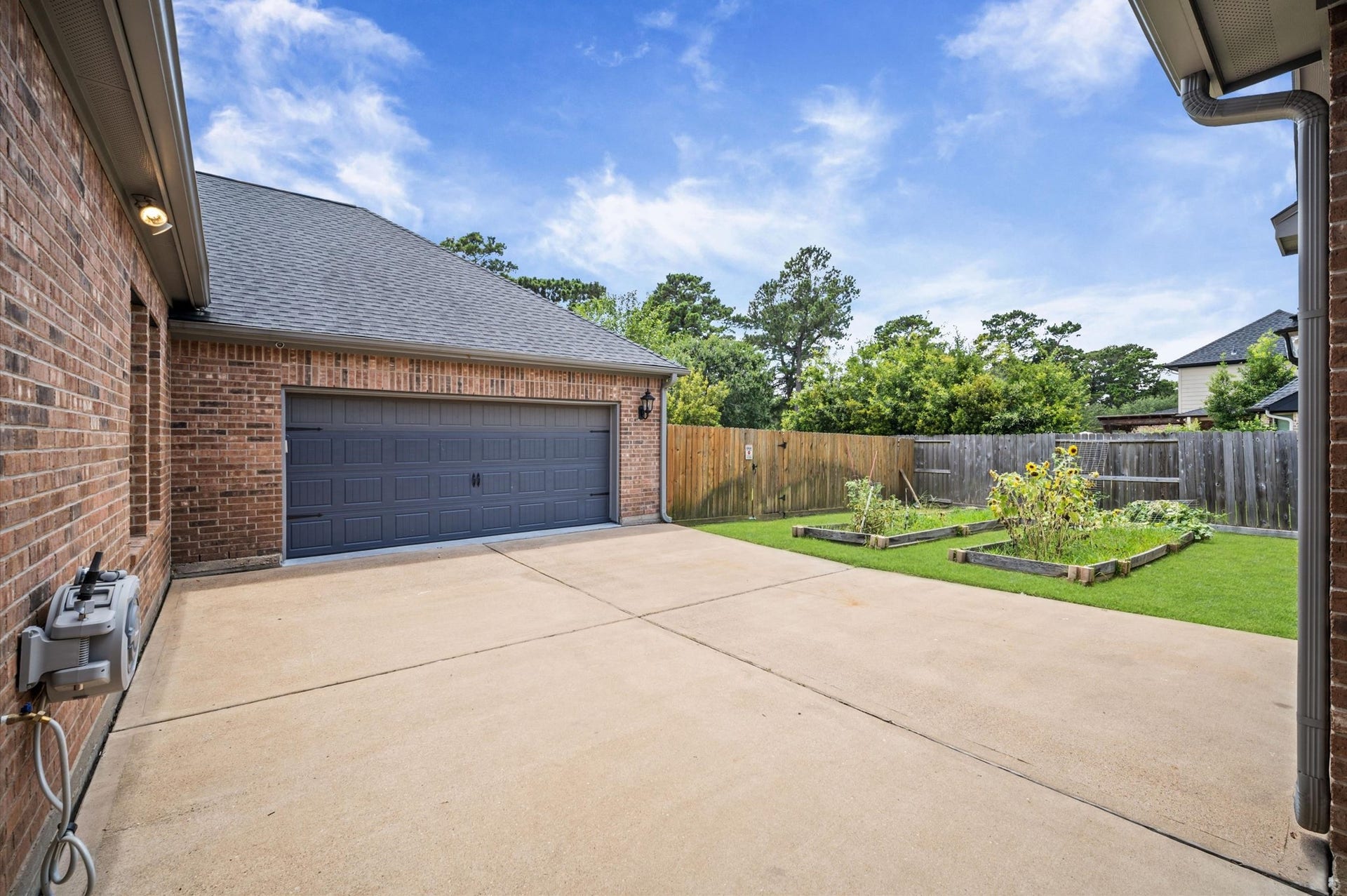 24611 Waterstone Estates Circle S, Tomball, TX 77375 A retractable garden hose rests on the left side of the driveway for reaching the planter boxes.