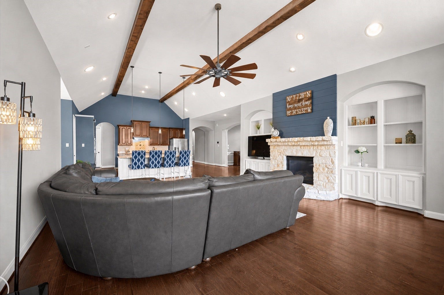 24611 Waterstone Estates Circle S, Tomball, TX 77375 Another view from the living room toward the kitchen. Note the stone accents on the gas fireplace as they complement the exposed beams and wood floors. Built-ins rest on either side for your favorite displays as well as cabinet storage.