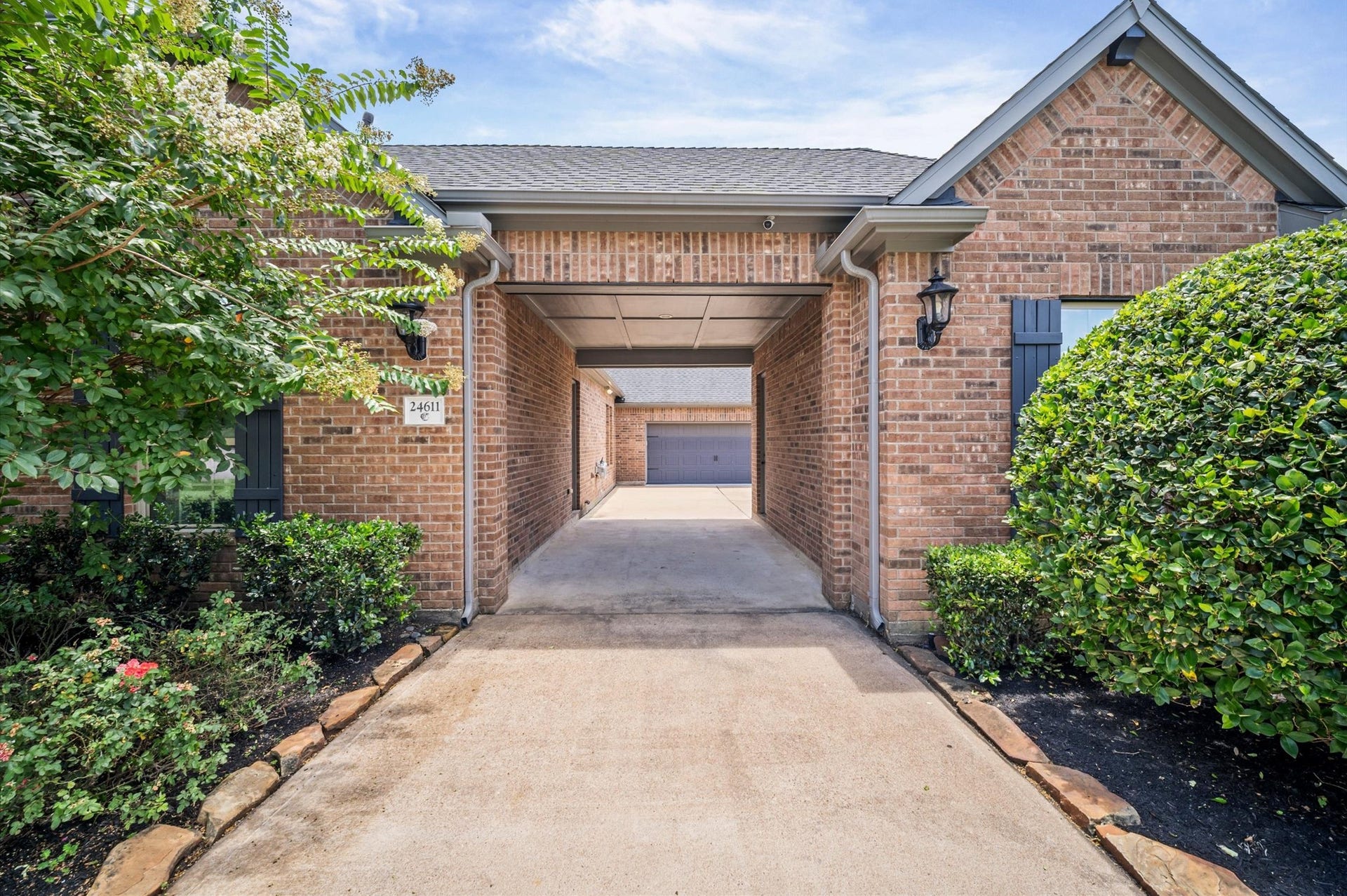 24611 Waterstone Estates Circle S, Tomball, TX 77375 From the front of the home, this is a view of the port-cochre as you head to the garages. Notice the landscaping on either side of the driveway, providing a warm welcome home.