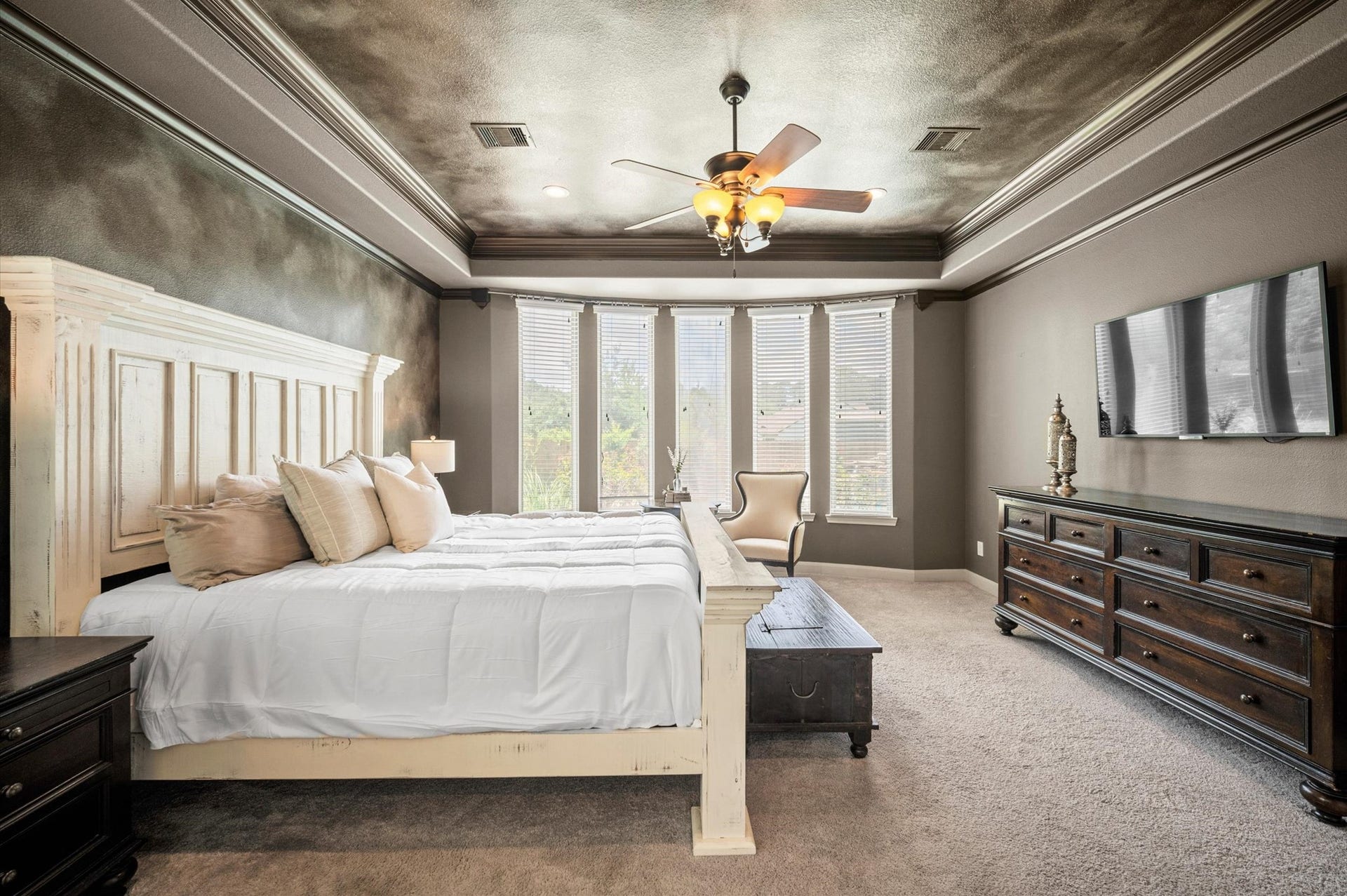 24611 Waterstone Estates Circle S, Tomball, TX 77375 An incredible primary suite offers a tray ceiling, a wall of windows, and plenty of space for a king-sized bed, side tables, and even a sitting area.