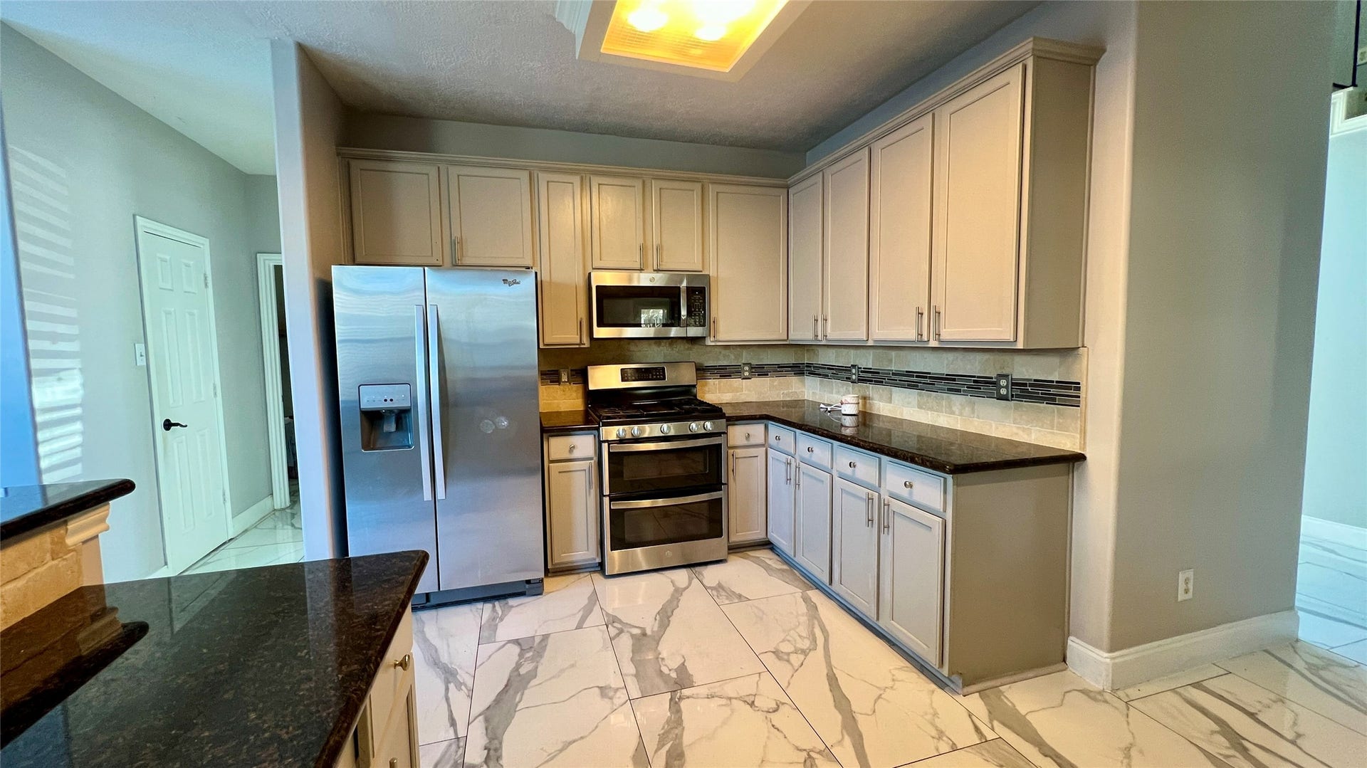 This modern kitchen features w/ granite countertops and stylish backsplash add a touch of sophistication.
