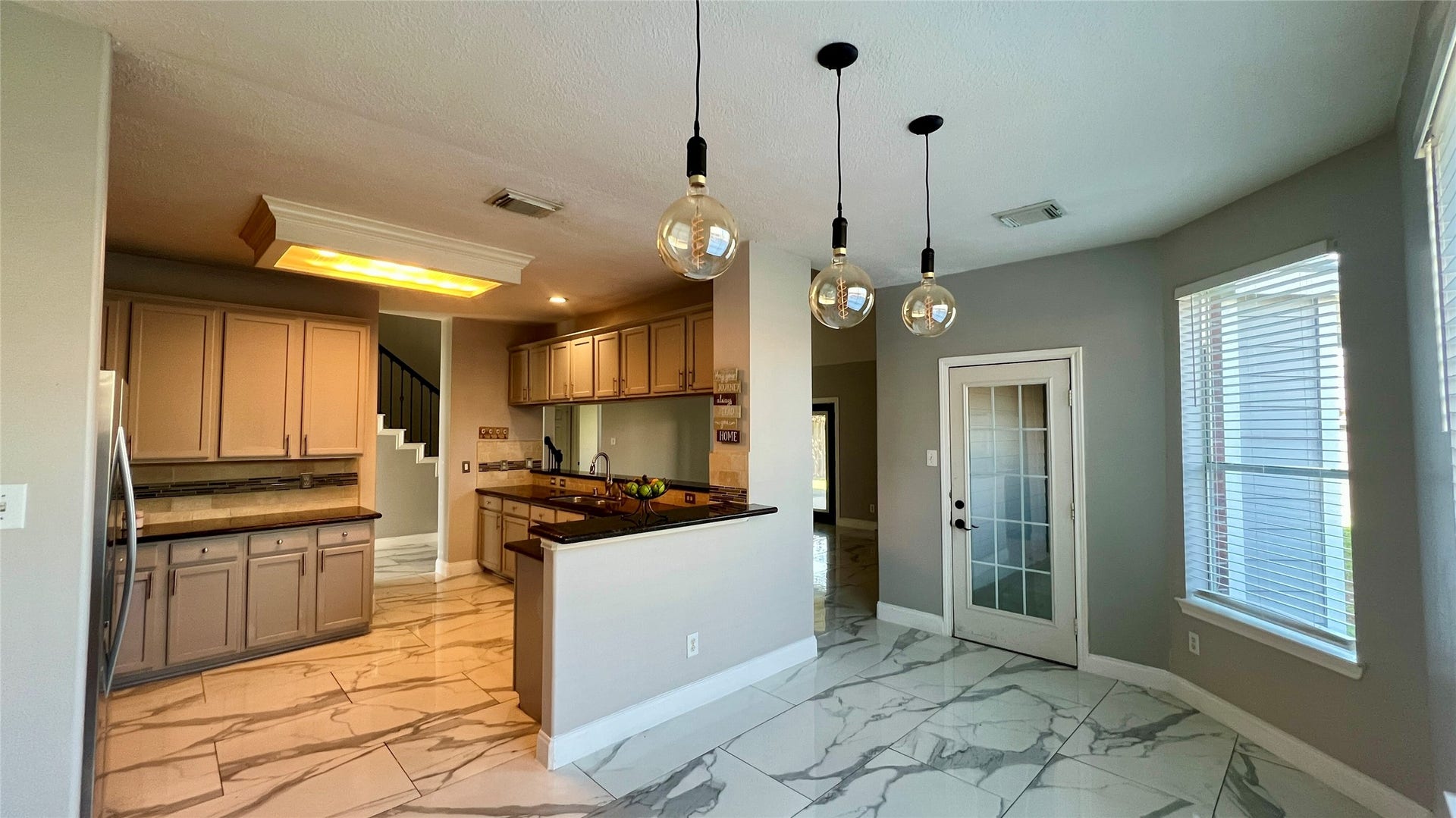 Bright kitchen with modern pendant lighting, and marble-style tile flooring. Features a breakfast nook.