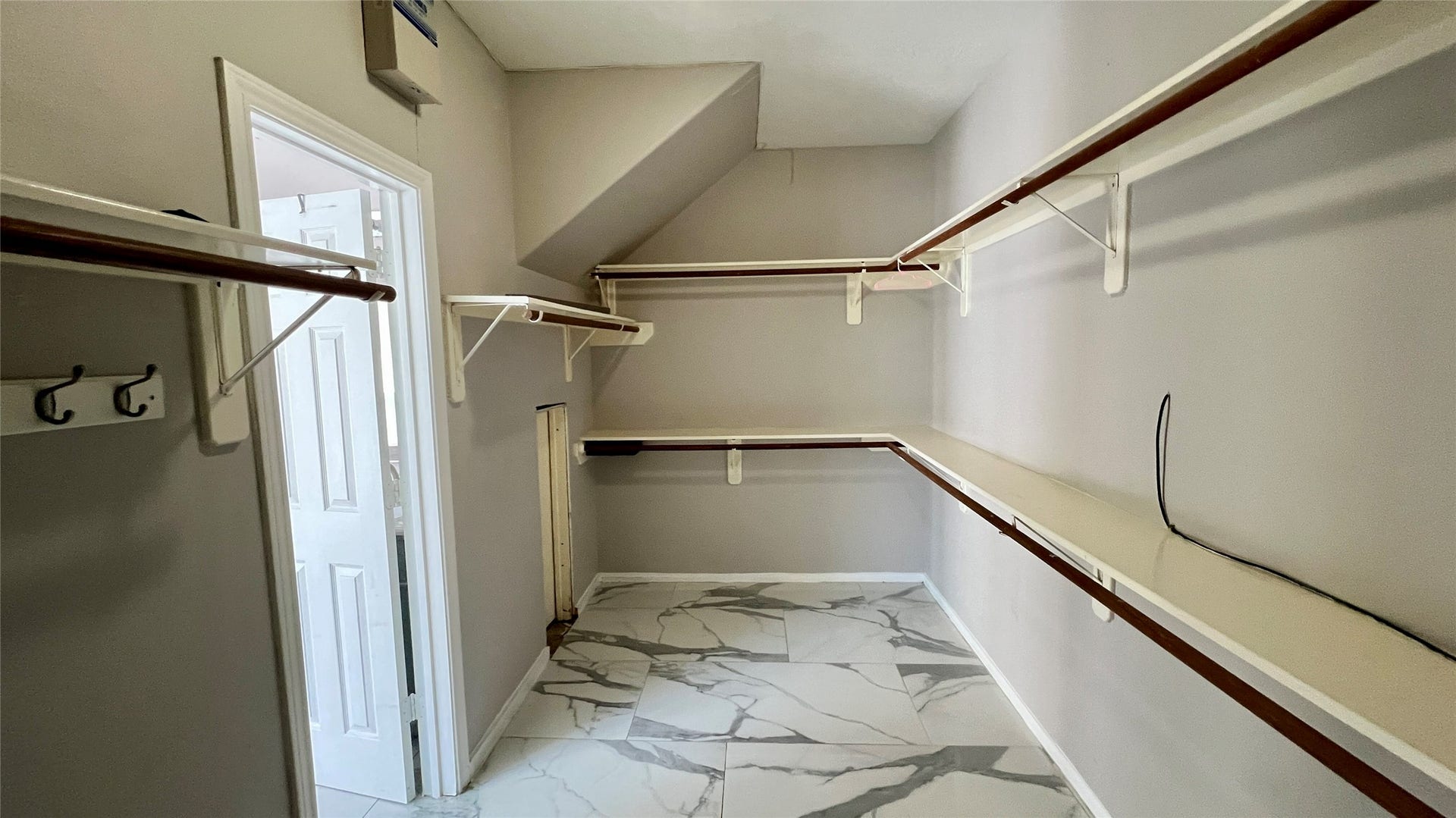 This spacious walk-in closet features multiple wooden shelves and hanging rods, with a modern