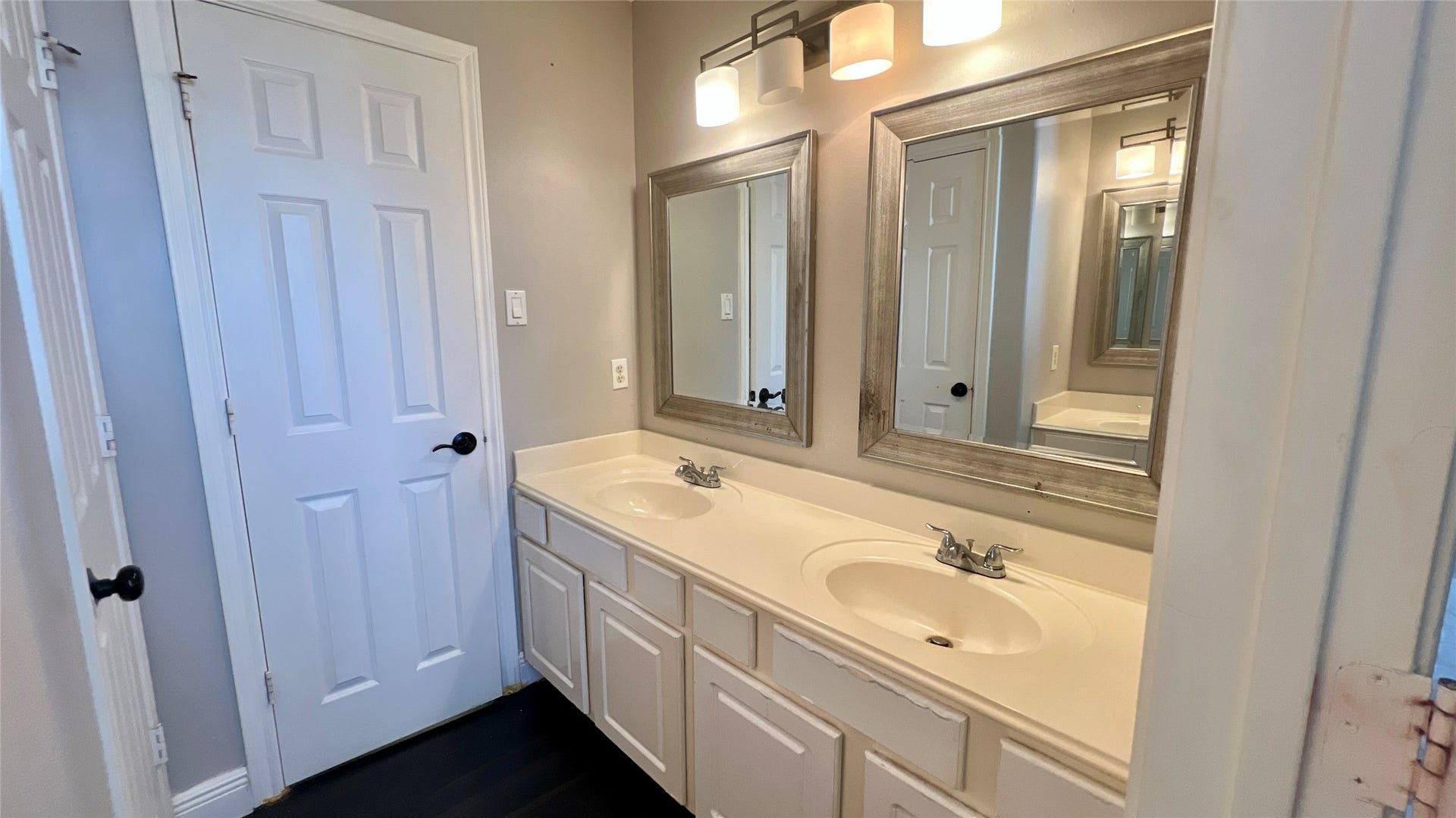 This bathroom features a double vanity with elegant framed mirrors and modern lighting, offering ample space and a stylish touch.