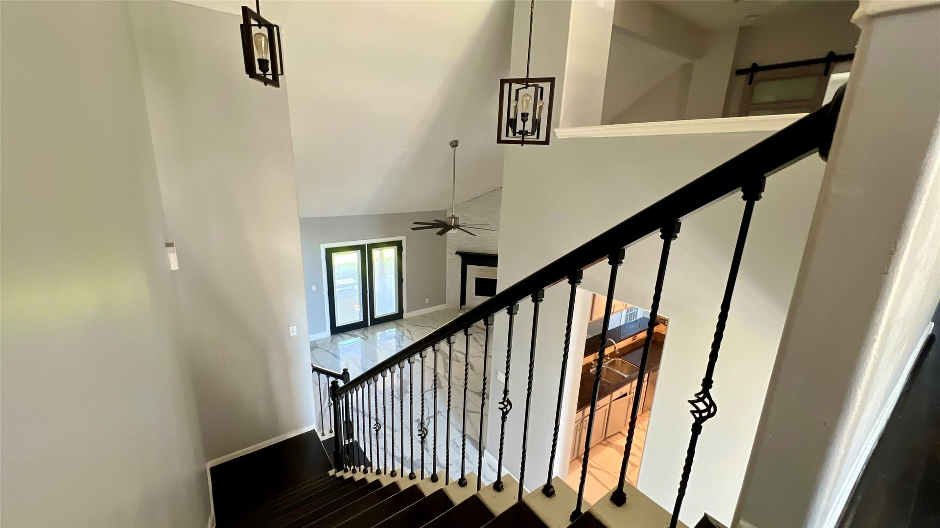 Modern interior with a high ceiling and a staircase featuring dark wood steps and elegant wrought iron railings.