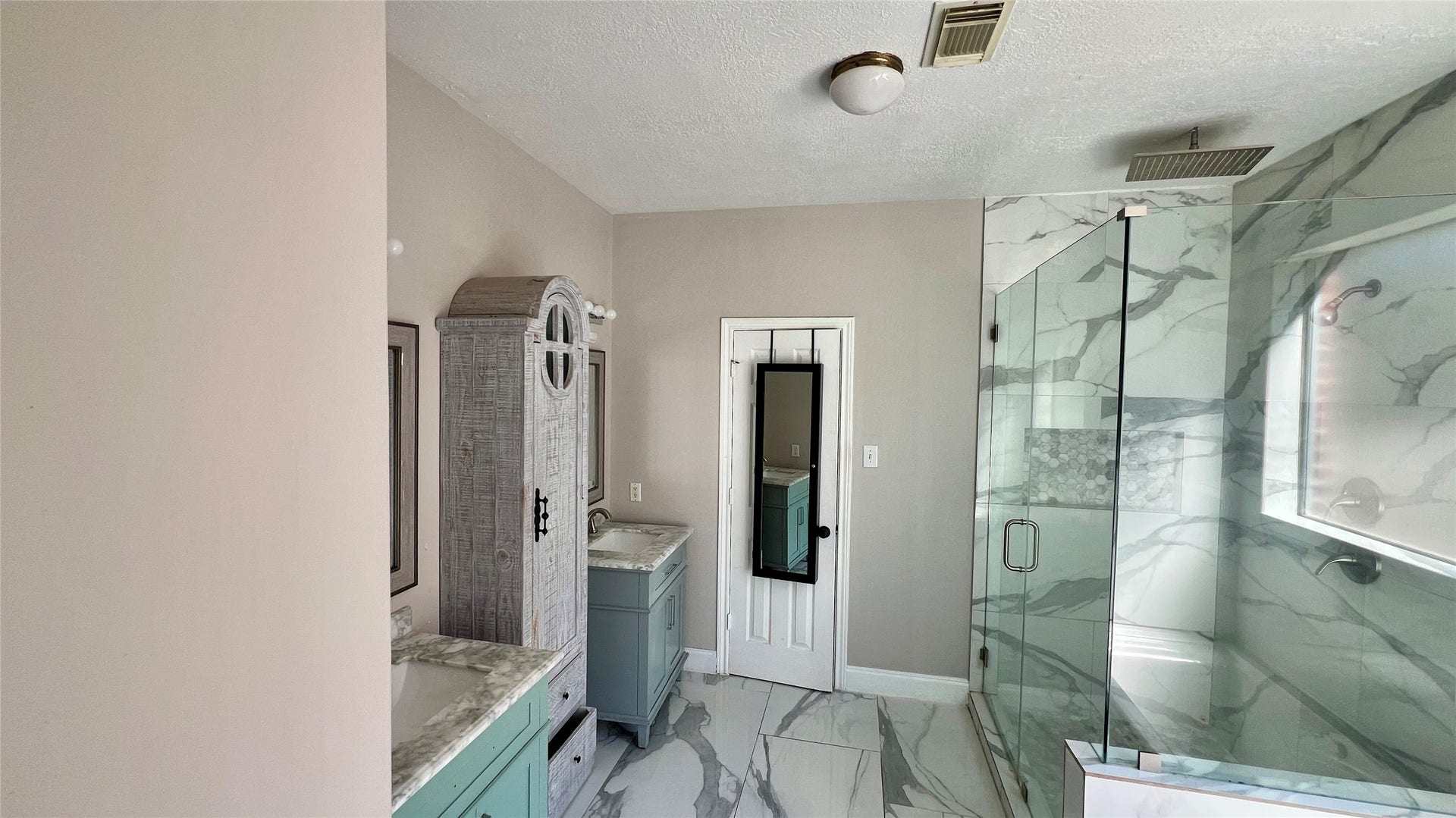This bathroom features modern elements with a spacious glass-enclosed shower, dual sinks.