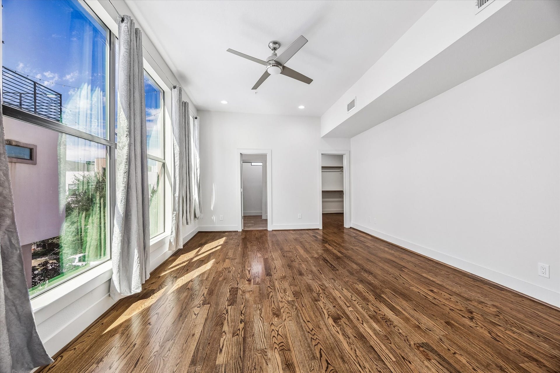 1215 Summer Street, #A, Houston, TX 77007 Alternate view of the primary bedroom highlighting expansive windows, a walk-in closet with built-in shelving and hanging space, and access to the adjoining bathroom.