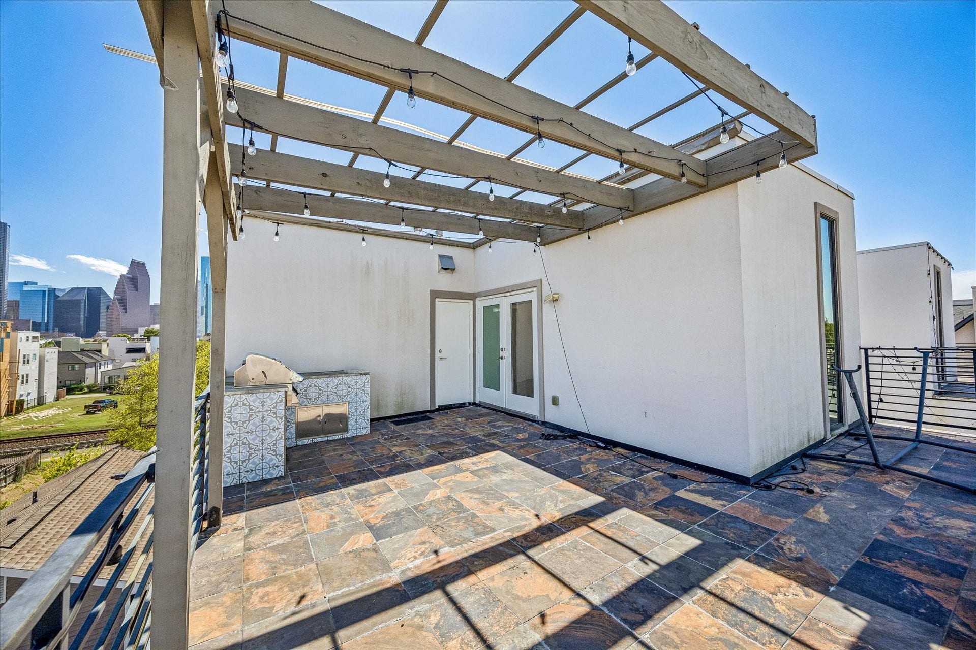 1215 Summer Street, #A, Houston, TX 77007 Alternate terrace view highlighting the pergola, built-in grilling station, and French doors connecting to the interior. The open layout provides room for outdoor entertaining with skyline views.