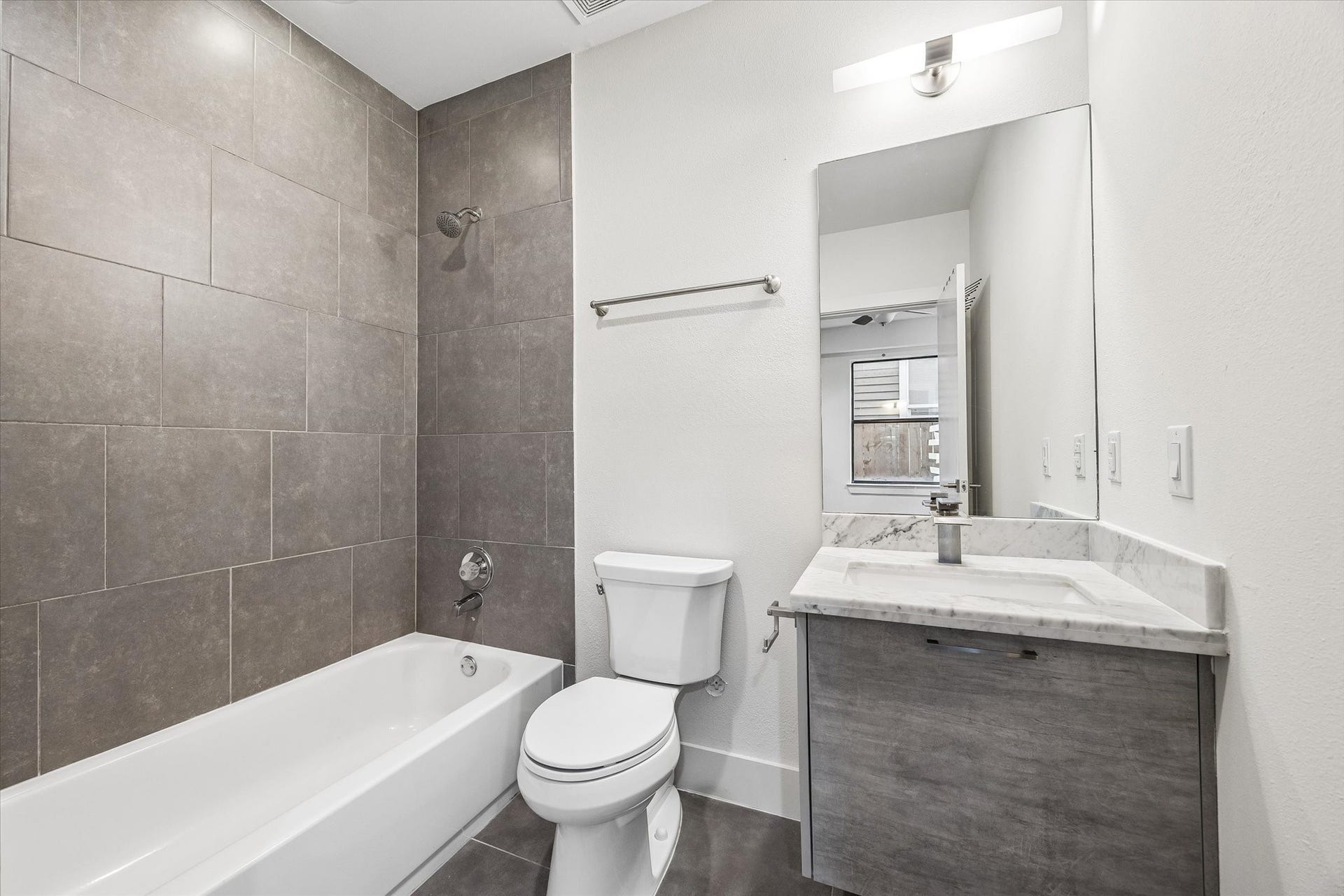 1215 Summer Street, #A, Houston, TX 77007 Full bathroom with a tub/shower combination, full-height tile surround, tile flooring, and a vanity with an undermount sink and cabinet storage.