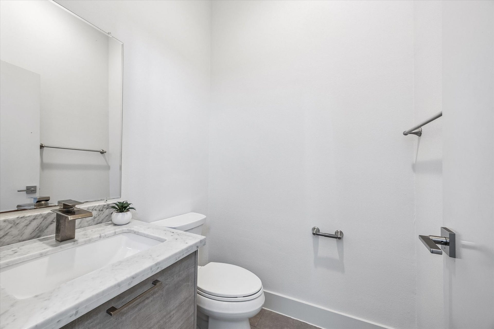 1215 Summer Street, #A, Houston, TX 77007 Convenient powder room featuring a vanity with a veined countertop, an undermount sink, cabinet storage, and a large mirror.