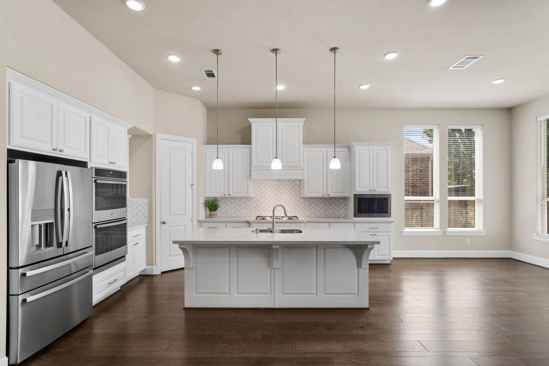 9410 Mount Logan, Missouri City, TX 77459 The heart of the home, this beautifully designed kitchen showcases an oversized center island, abundant custom cabinetry, stainless steel appliances, double ovens, and a timeless herringbone tile backsplash.