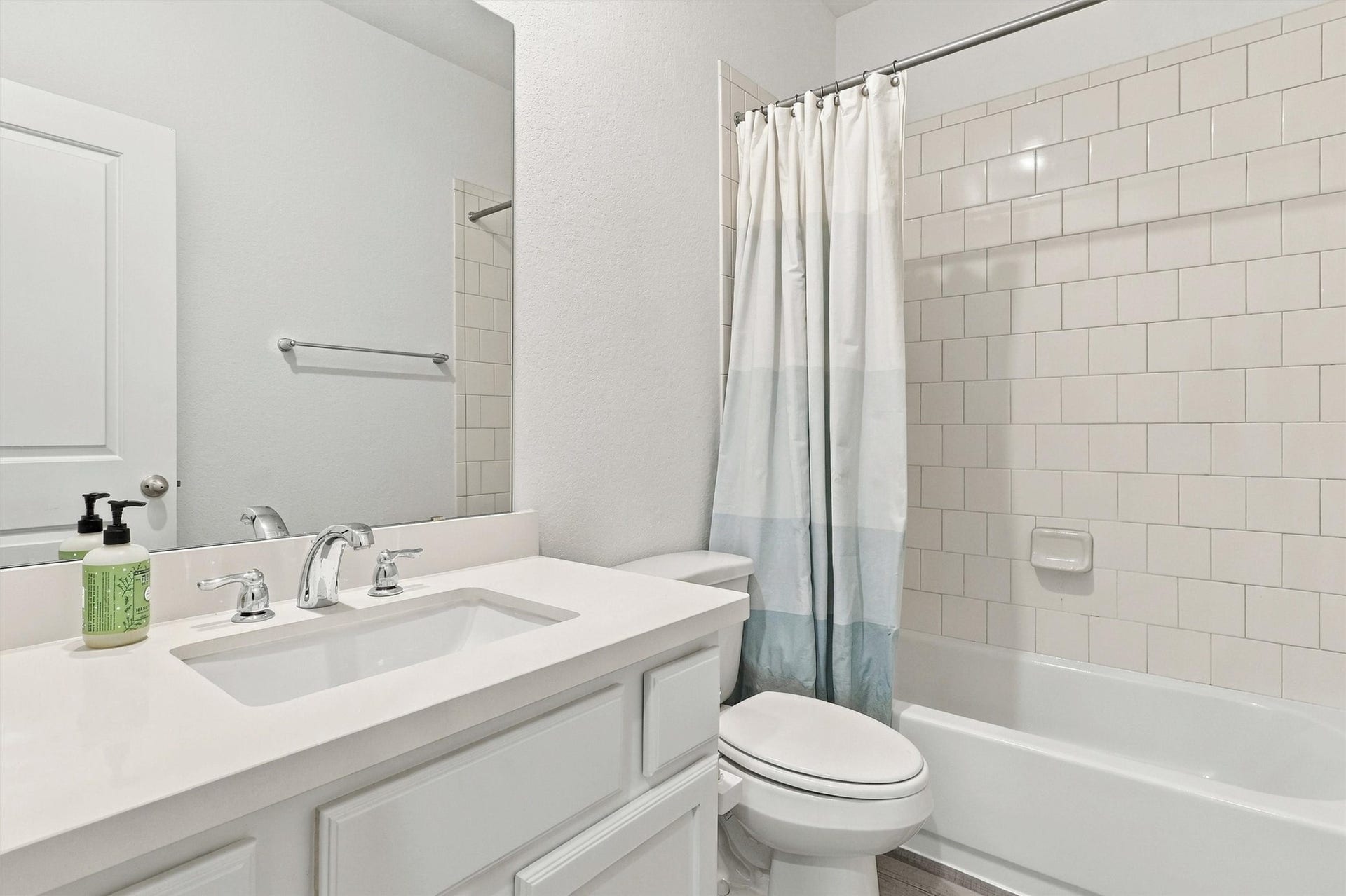 13109 Blue Flora Drive, Texas City, TX 77568 Second full bath, beautifully done in white tile and timeless silver accents. This bathroom features solid surface countertop and undermount sink, white vanity, and shower/tub combo!