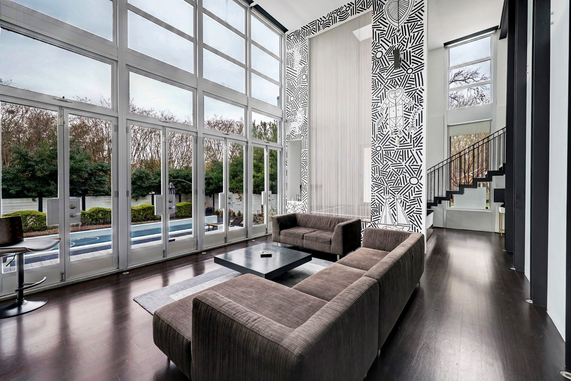 2200 Harvard Street, Houston, TX 77008 The eclectic living room prominently features soaring ceilings and dramatic oversized windows that are sure to be awe-inspiring. The black and white wall mural is a true work of art, adding a touch of sophistication to the space.