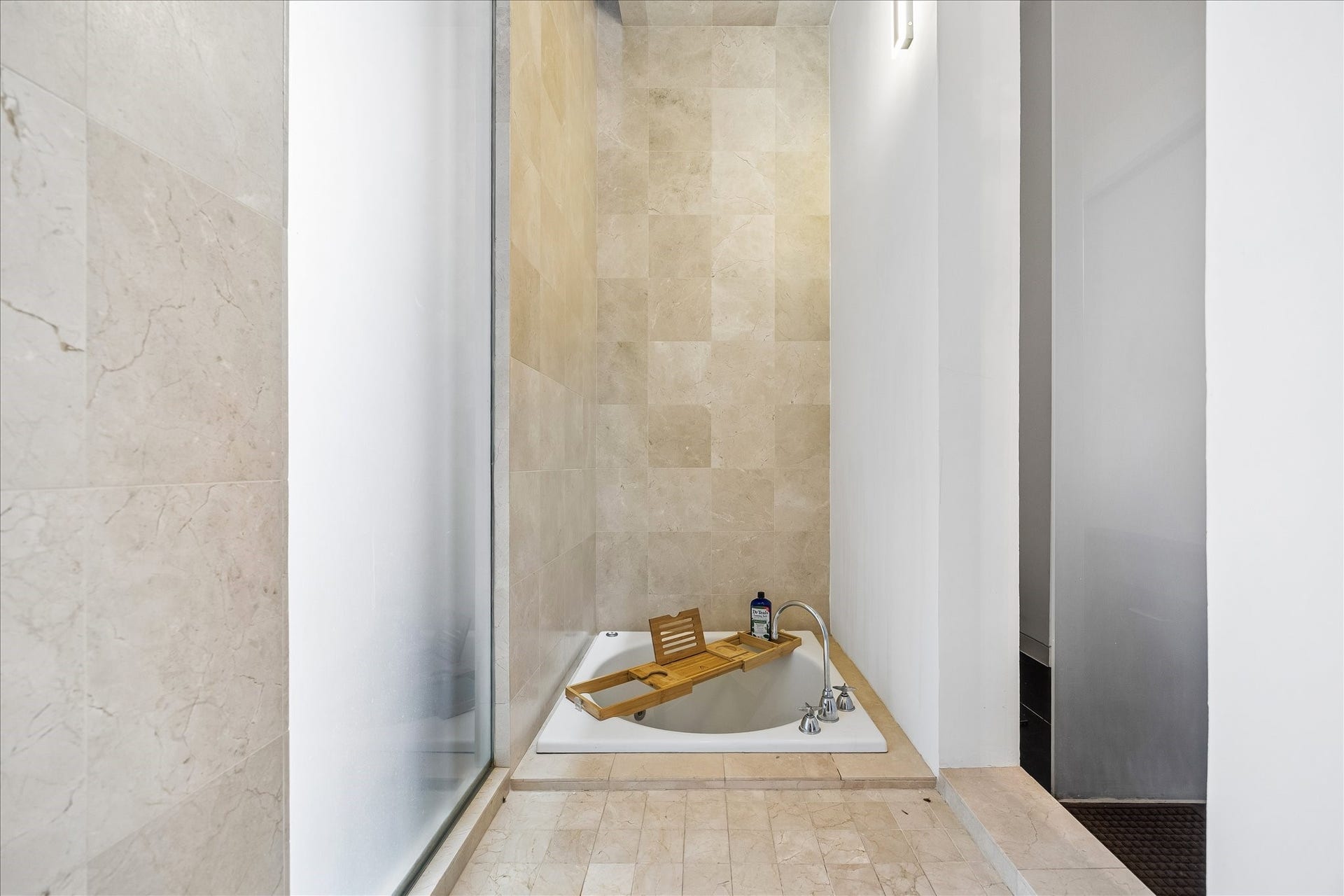 2200 Harvard Street, Houston, TX 77008 A Japanese soaking tub creates a serene focal point within the Jack-and-Jill bath, surrounded by warm stone tile and softly diffused natural light.