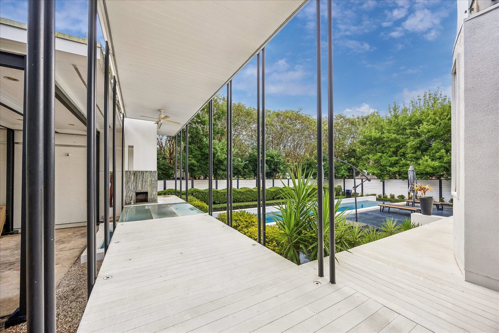 2200 Harvard Street, Houston, TX 77008 Slender black columns frame a covered walkway overlooking the pool, highlighting the homes strong architectural lines and seamless connection between indoor and outdoor spaces.