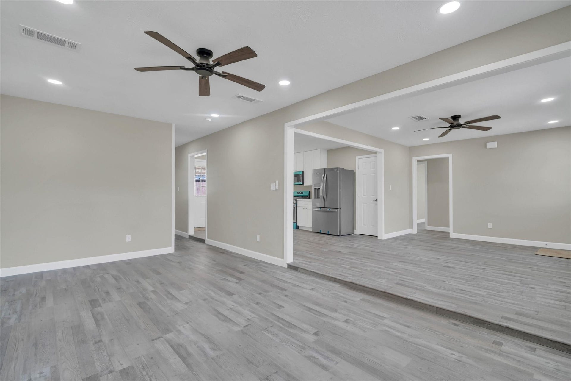 Spacious open-concept living area leading into a sleek kitchen with stainless steel appliances.