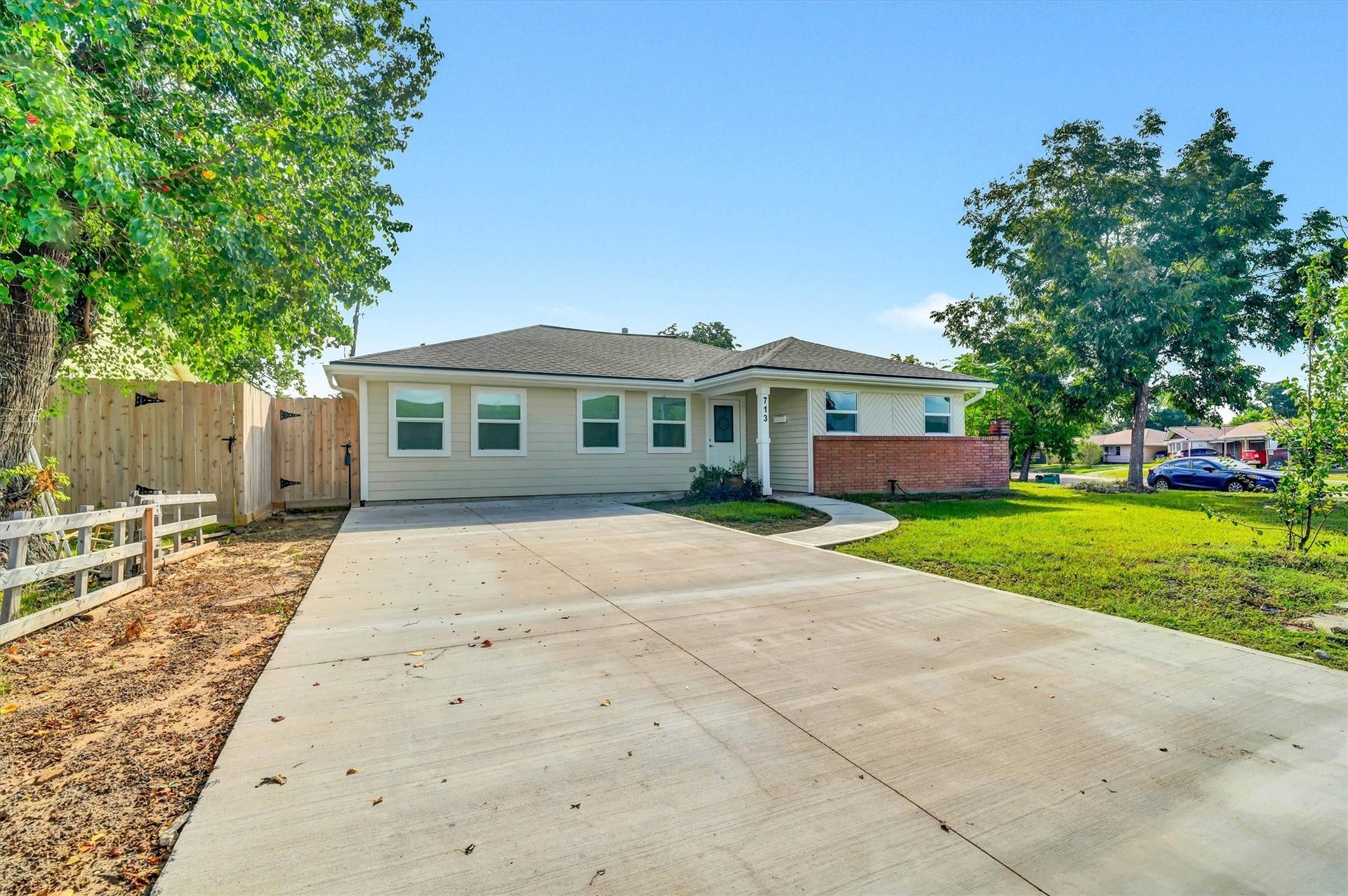 Single-story home with fresh exterior, expansive private driveway, and large front yard.