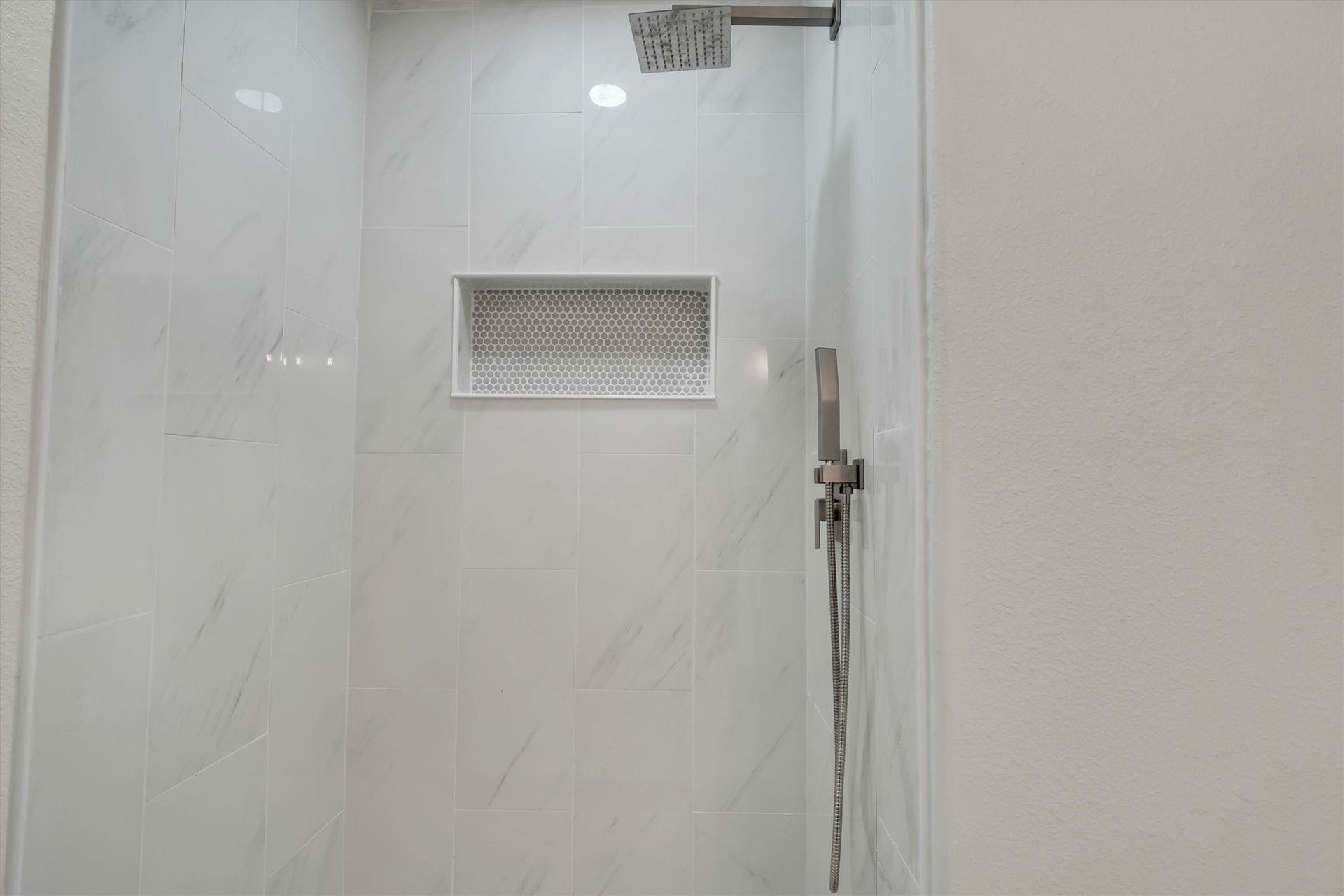 Elegant shower with polished tile, modern fixtures, and a stylish built-in niche for convenience.