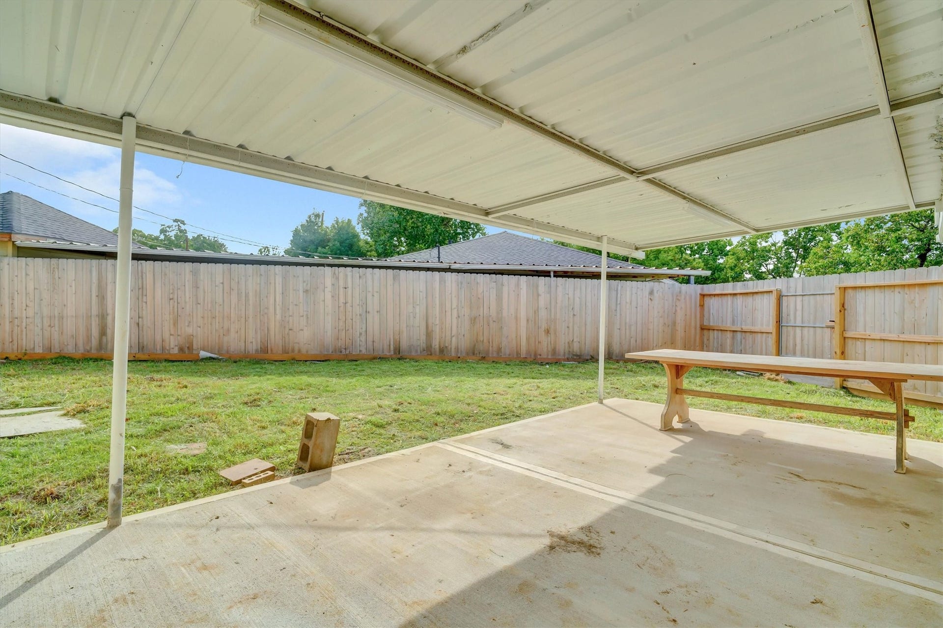 Spacious covered patio overlooking a private fenced backyard, perfect for outdoor gatherings and relaxation.