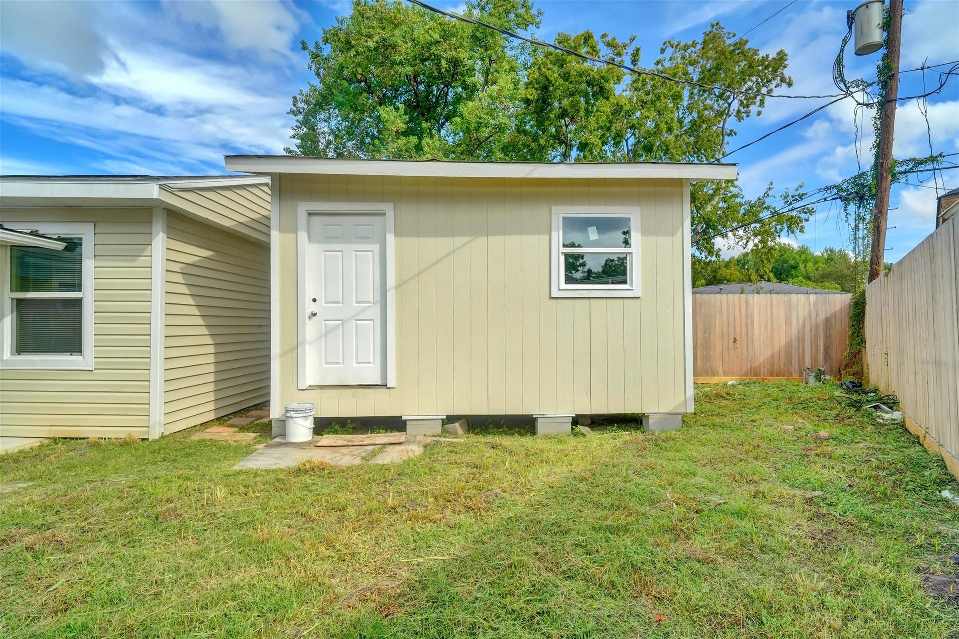 Charming backyard space with a small, detached shed featuring a single door and window, perfect for storage or a workshop.