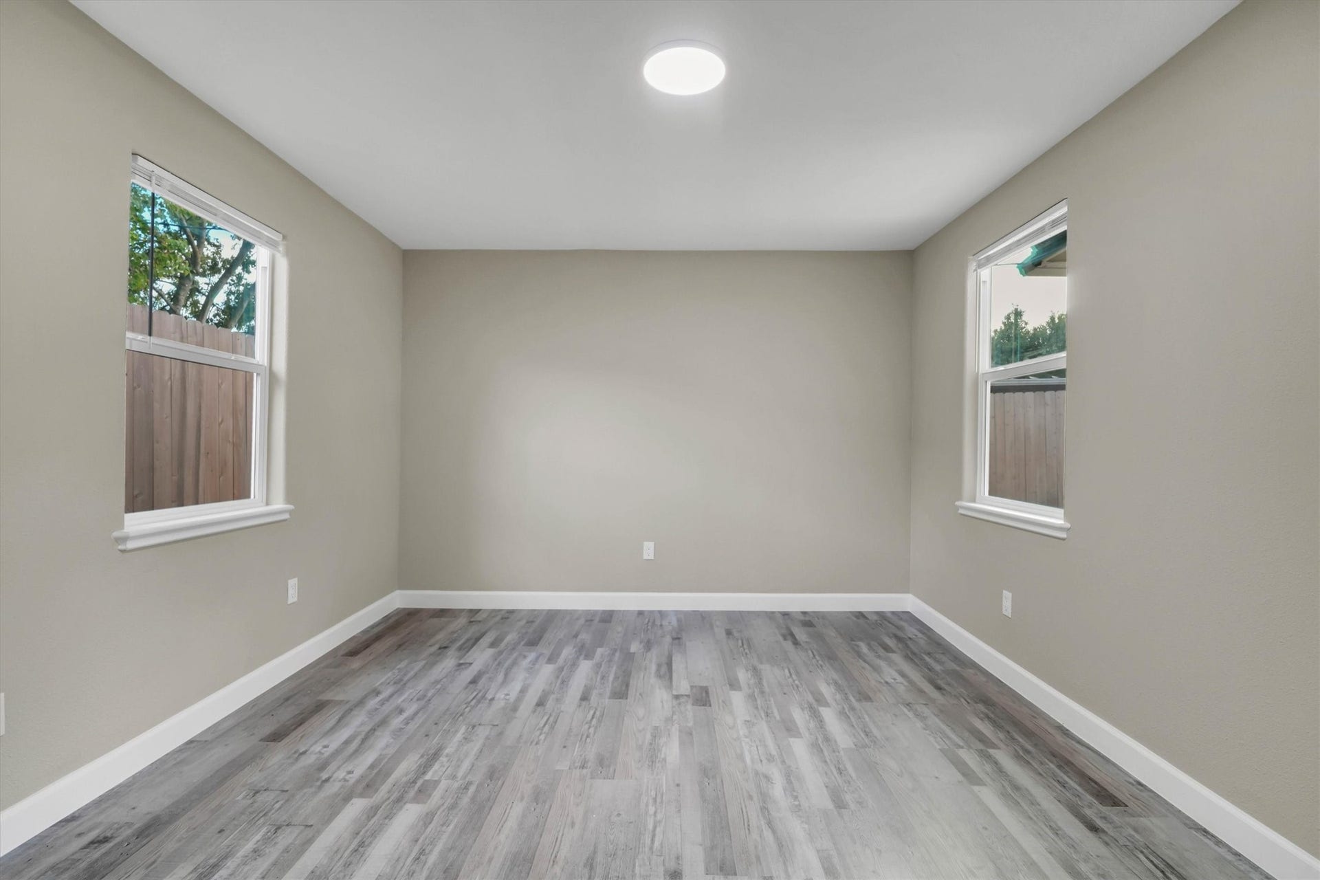 Spacious secondary bedroom with fresh neutral walls, sleek flooring, and plenty of natural light from dual windows.