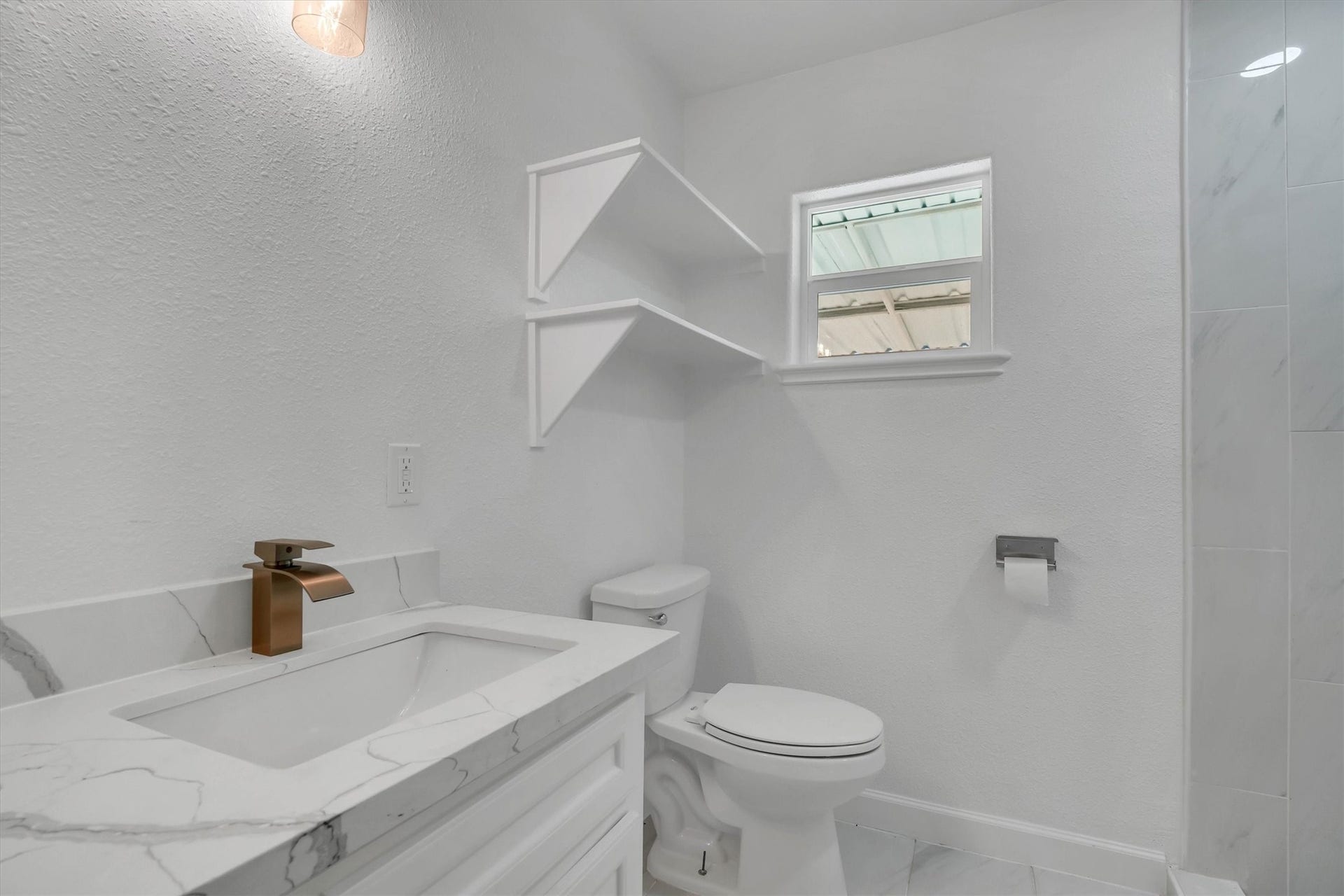 Bright and modern bathroom featuring a sleek countertop, elegant fixtures, and ample natural light.