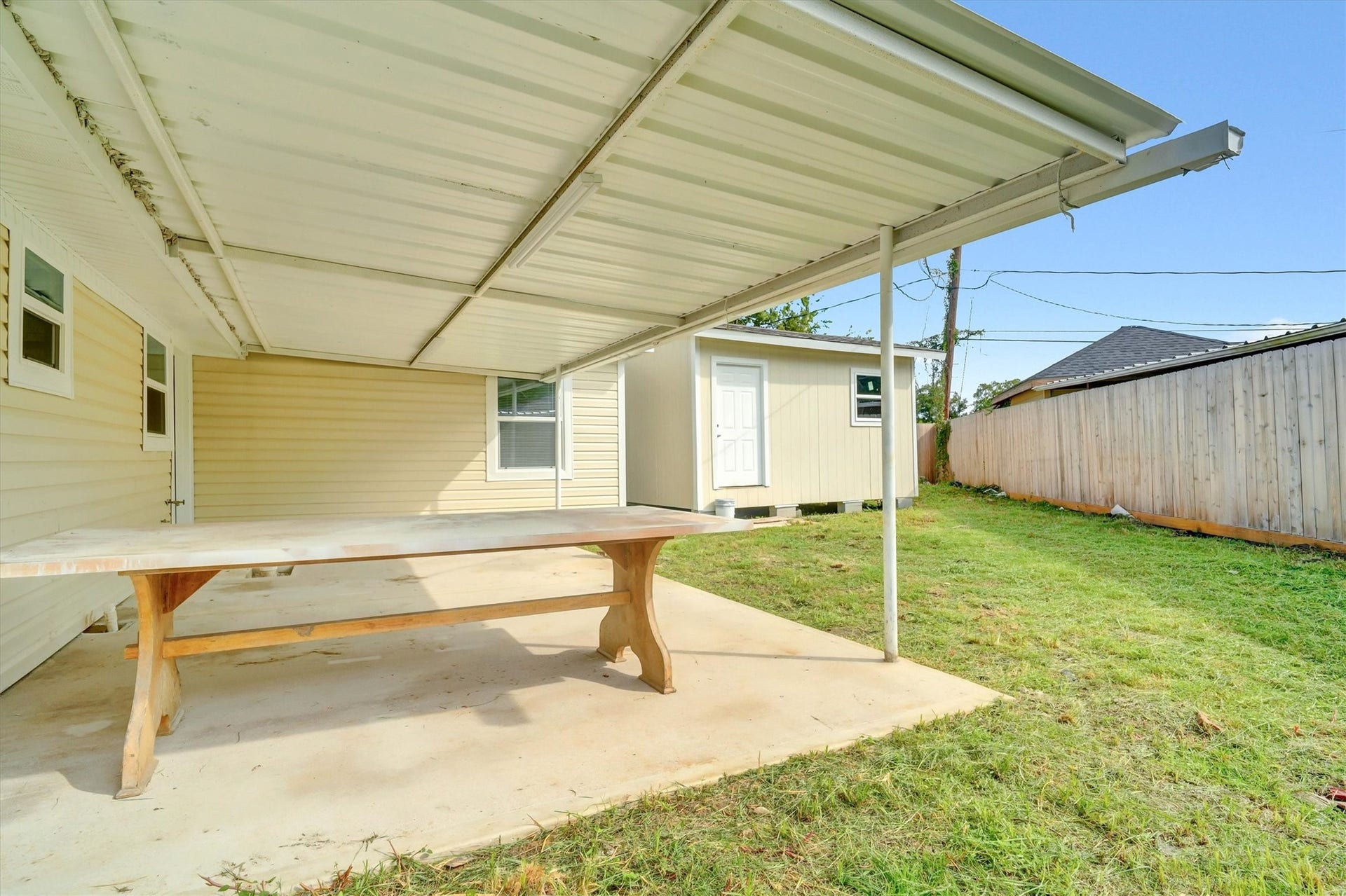Spacious backyard features a covered patio, perfect for outdoor dining and relaxation, with a storage shed and privacy fencing.