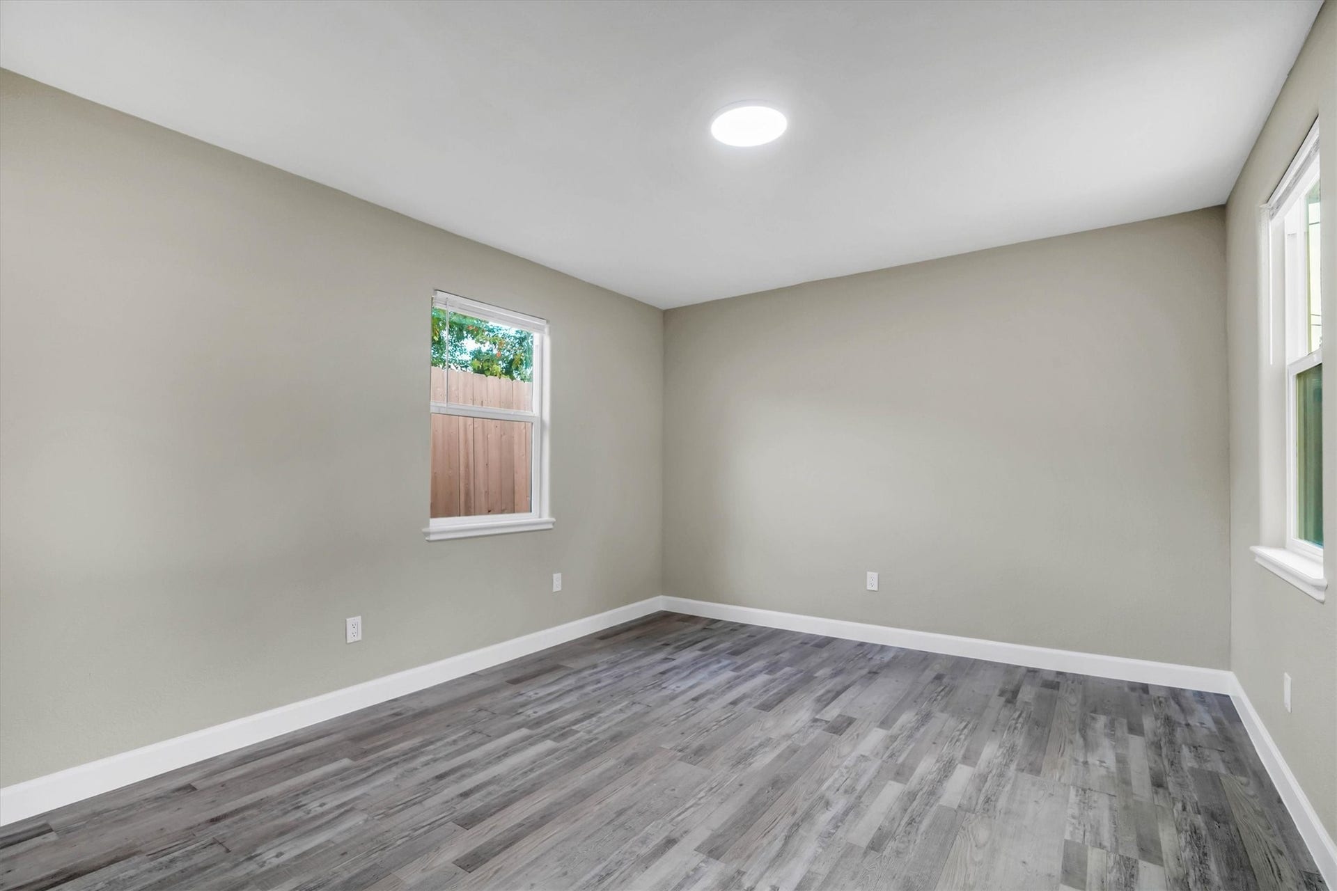Primary bedroom with sleek flooring and ample natural light from large windows.