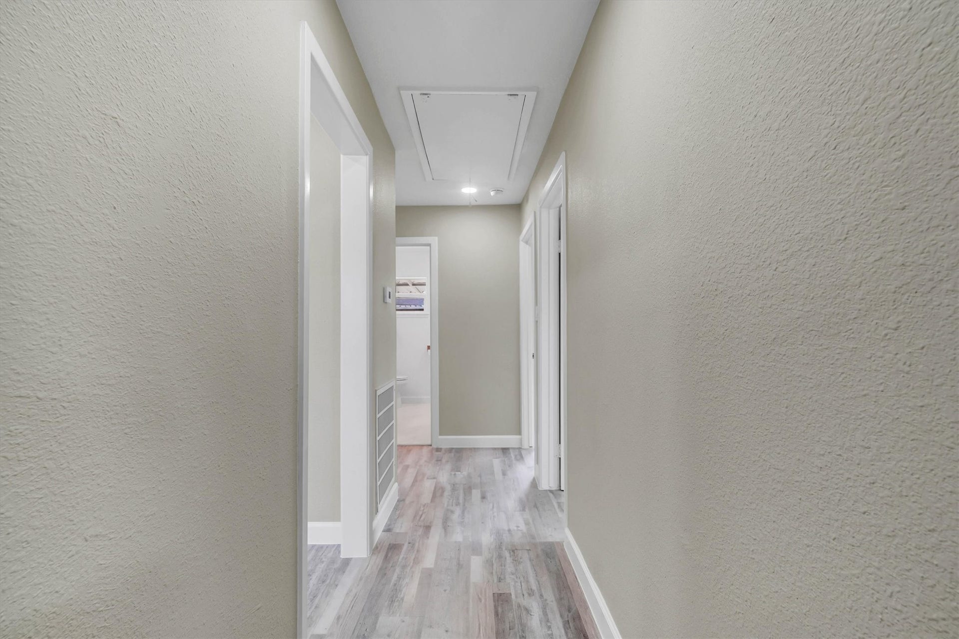 Bright and inviting hallway with neutral walls and modern flooring, leading to multiple rooms.