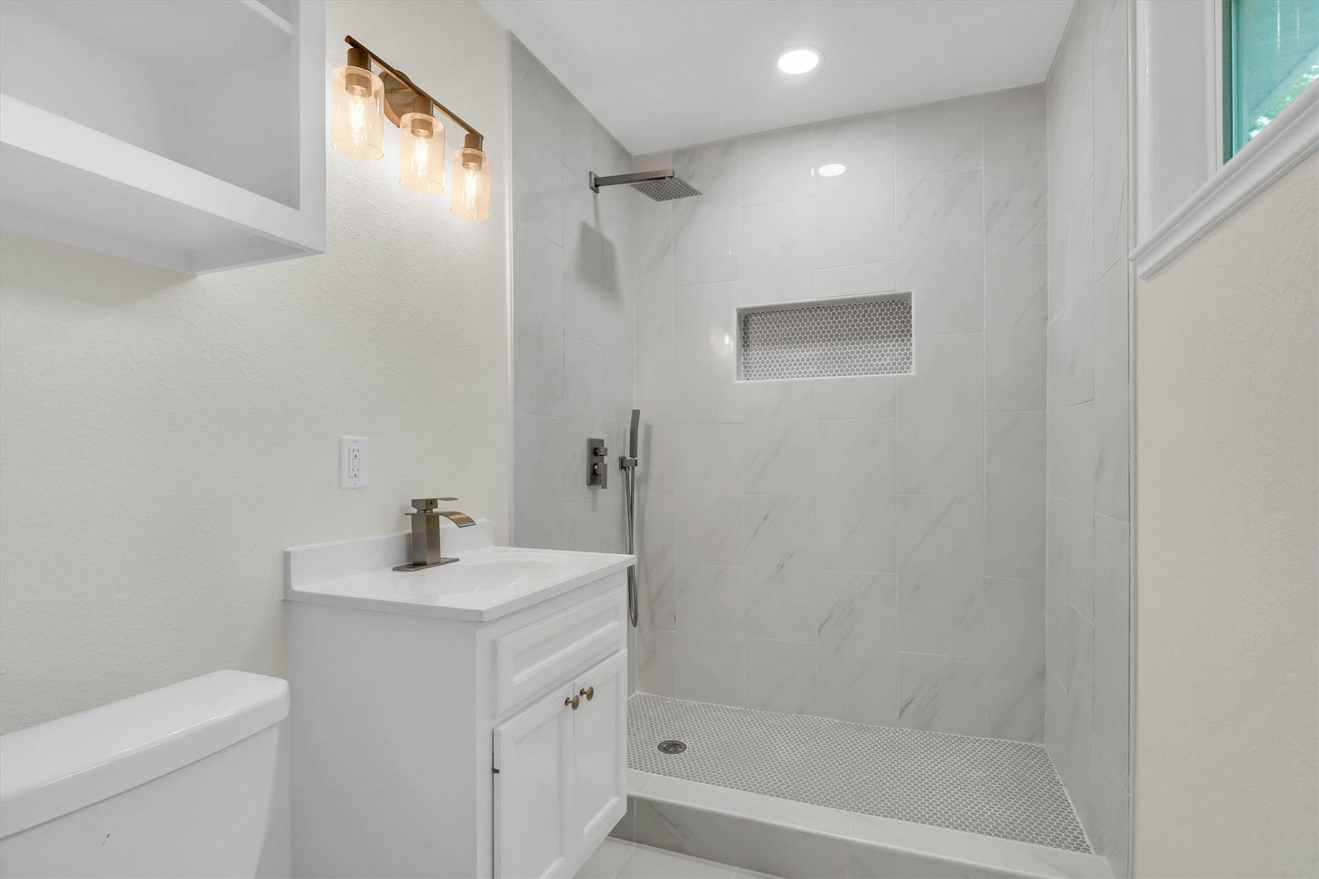 Modern bathroom featuring a sleek walk-in shower with a rainfall showerhead and elegant tilework, complemented by a chic vanity and stylish lighting.