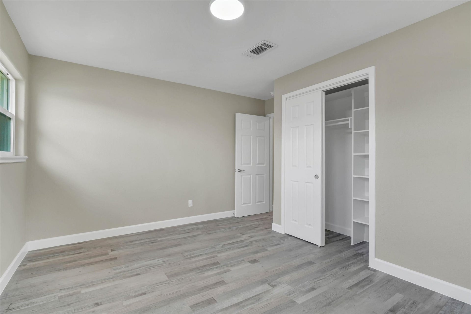 Secondary bedroom featuring a spacious closet with sliding doors, and abundant natural light from a large window.