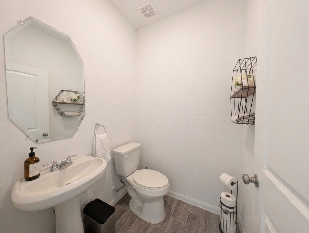 18122 Sonresa Way, Tomball, TX 77377 Half bathroom / powder room featuring a modern vanity, framed mirror, and commode.