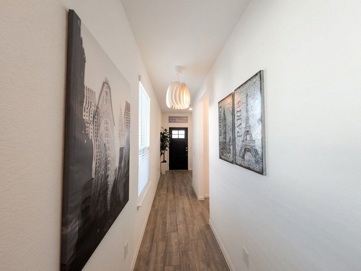 18122 Sonresa Way, Tomball, TX 77377 Interior hallway looking past framed artwork toward the living and kitchen areas.