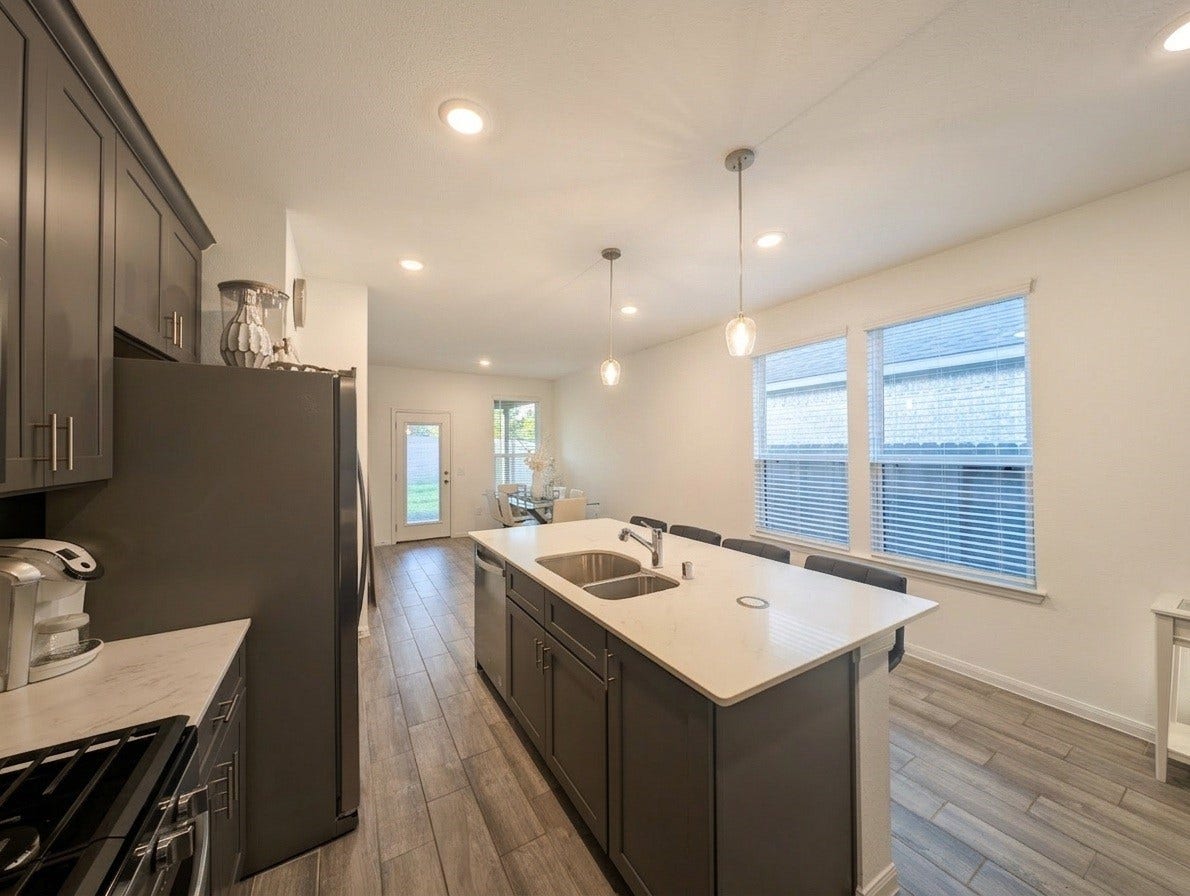 18122 Sonresa Way, Tomball, TX 77377 Open kitchen and dining corridor perspective showing the continuous flooring and airy ambiance.
