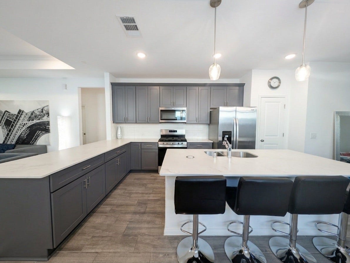 18122 Sonresa Way, Tomball, TX 77377 Gourmet kitchen showcasing dark cabinetry, white quartz countertops, stainless steel appliances, and pendant lighting over a large central island.