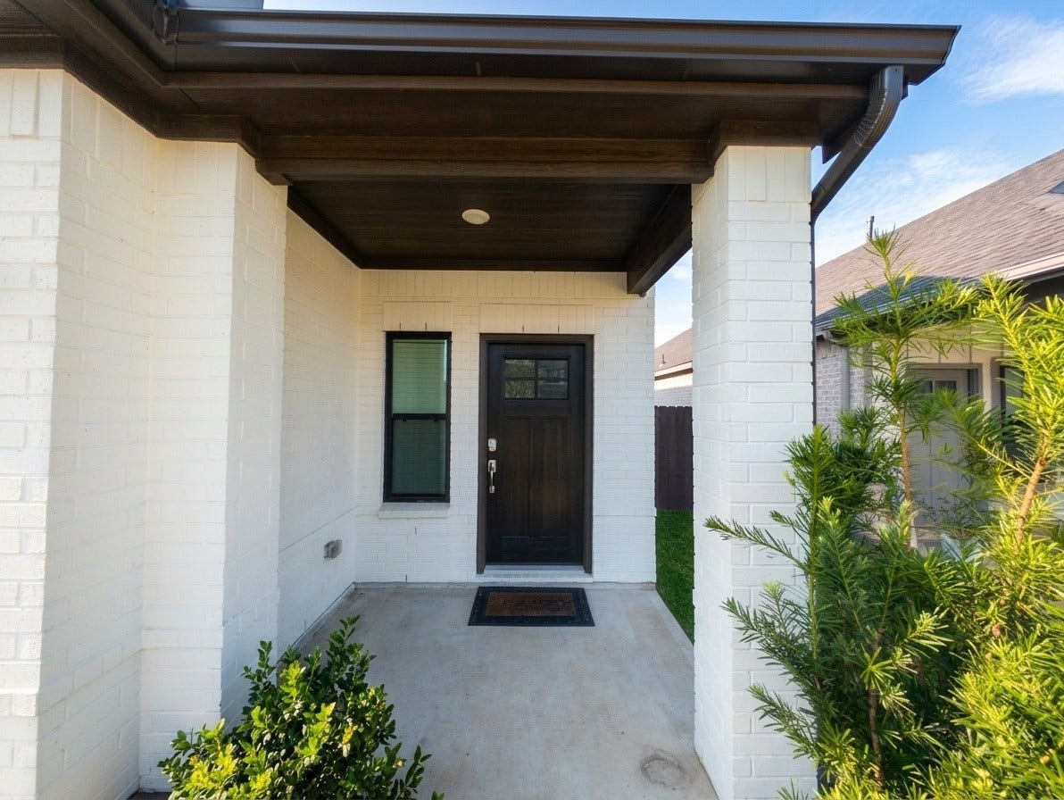 18122 Sonresa Way, Tomball, TX 77377 Covered front entryway and porch area with a modern front door, column details, and neat landscaping.