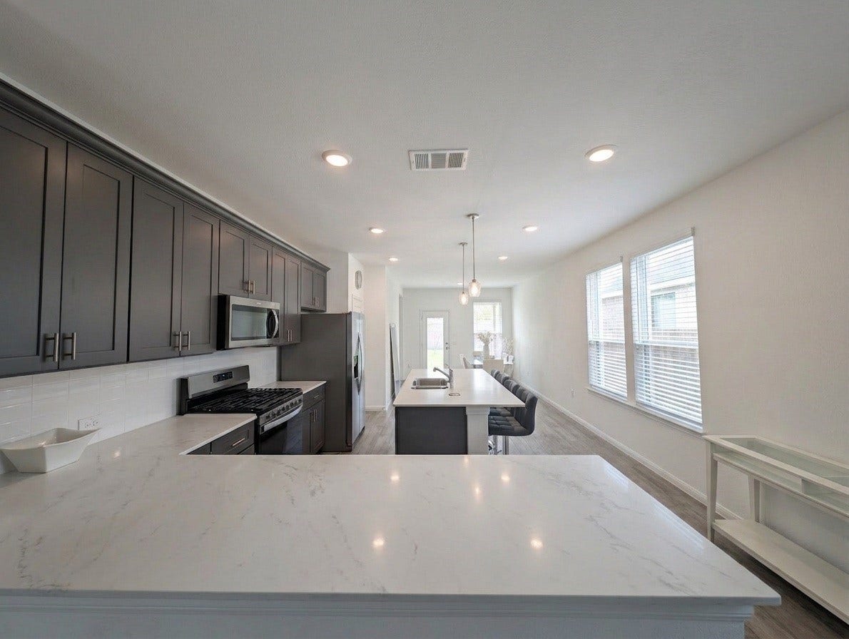18122 Sonresa Way, Tomball, TX 77377 View down the kitchen and utility corridor with ample natural light from surrounding windows.