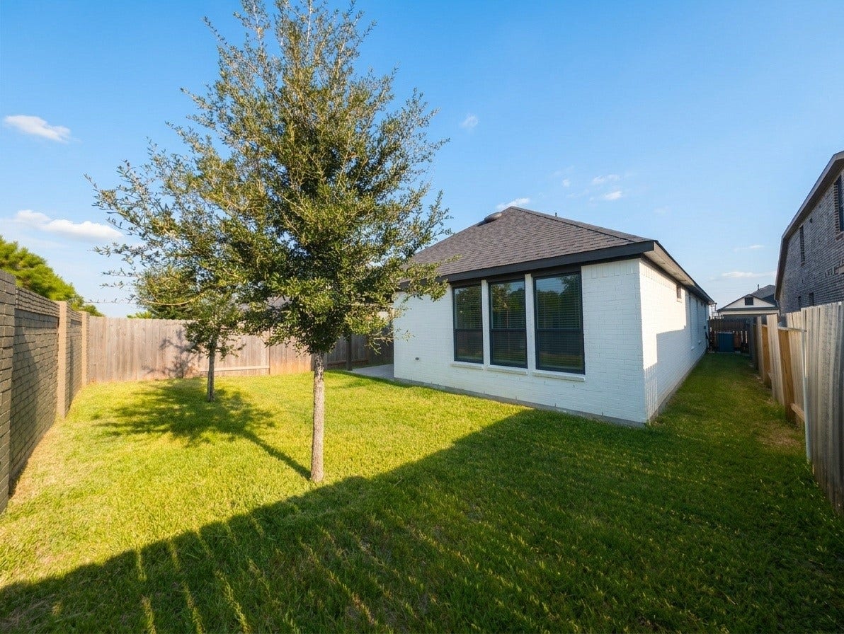 18122 Sonresa Way, Tomball, TX 77377 Wide-angle rear exterior view highlighting the property's backyard layout and roofline.